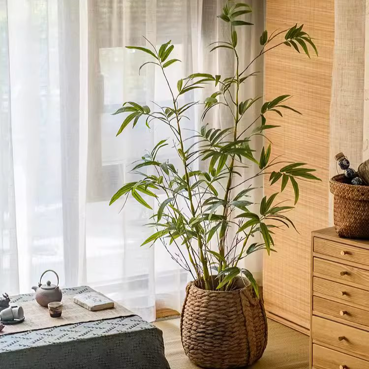 Lifelike artificial bamboo leaves in a black pot, showcasing vibrant green foliage.