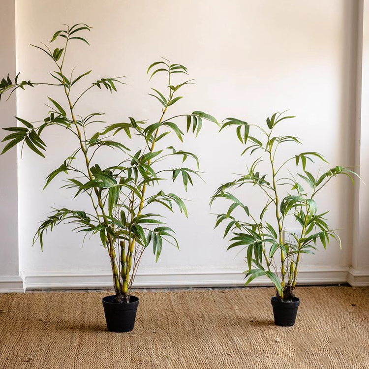 Lifelike artificial bamboo leaves in a black pot, showcasing vibrant green foliage.