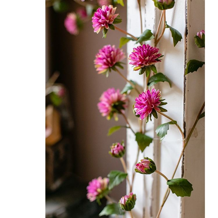 A long artificial chrysanthemum flower vine in rose color with green leaves, showcasing realistic silk flowers.