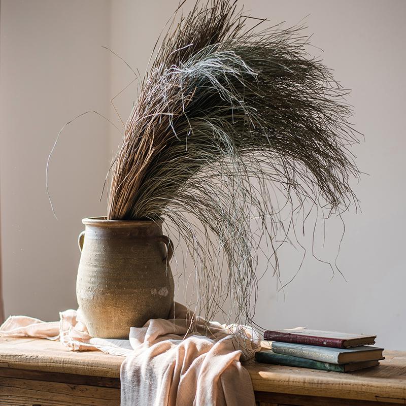 A bundle of artificial faux dried grass in green and khaki colors, showcasing its realistic texture and natural appearance.