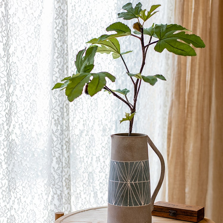 A tall Artificial Faux Fig Leaf Stem with lush green leaves, showcasing its realistic design and vibrant colors, perfect for home decor.