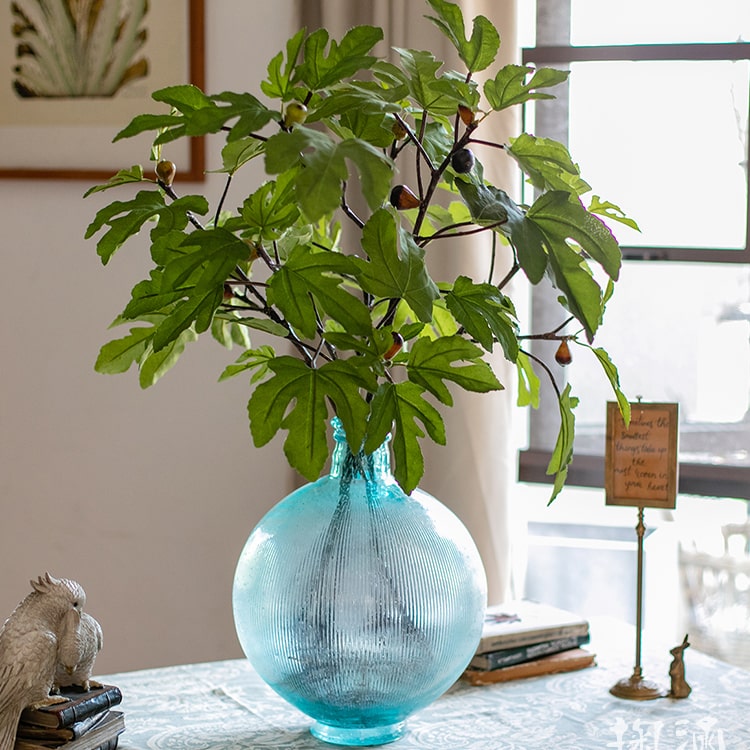 A tall Artificial Faux Fig Leaf Stem with lush green leaves, showcasing its realistic design and vibrant colors, perfect for home decor.