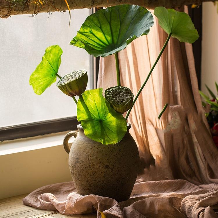 Artificial faux plant featuring lotus seed pods and large green leaves, available in various sizes for decorative arrangements.