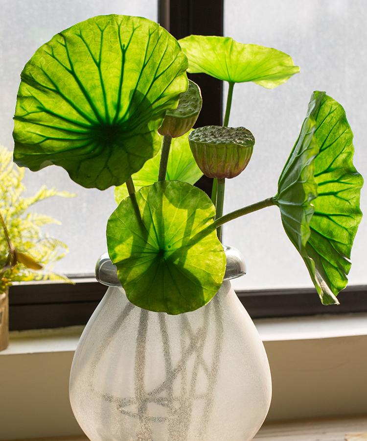 Artificial faux plant featuring lotus seed pods and large green leaves, available in various sizes for decorative arrangements.