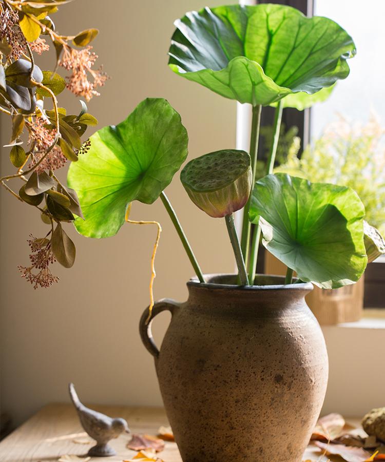 Artificial faux plant featuring lotus seed pods and large green leaves, available in various sizes for decorative arrangements.