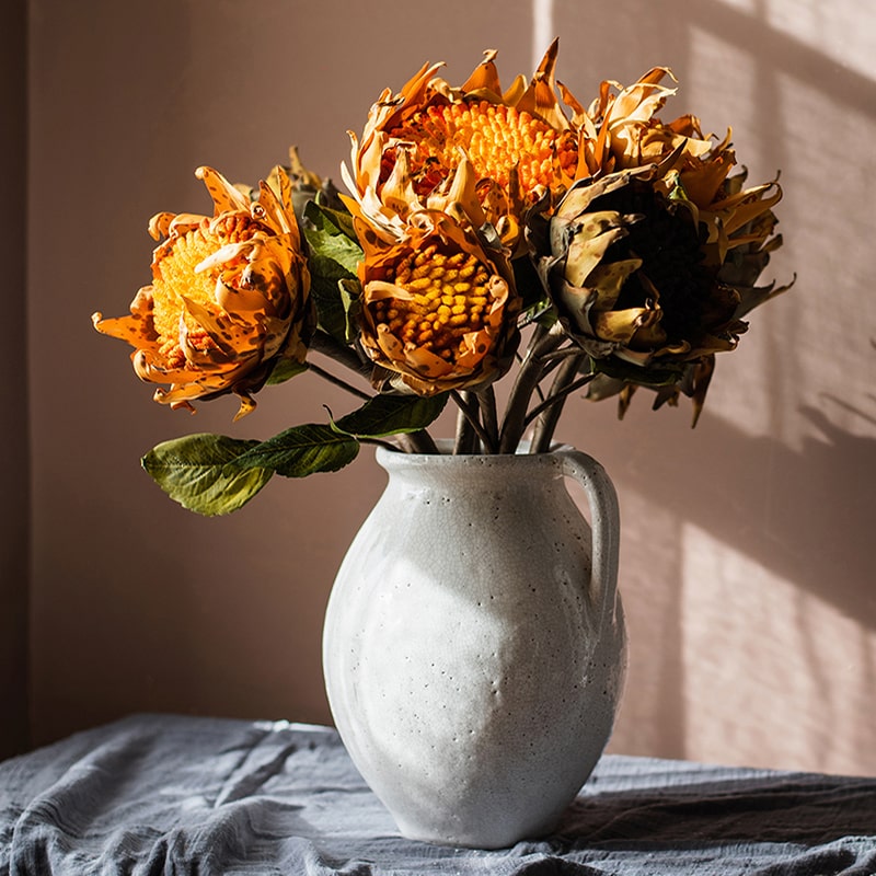 A vibrant artificial flannel sunflower stem featuring bright yellow petals and lush green leaves, perfect for home decor.