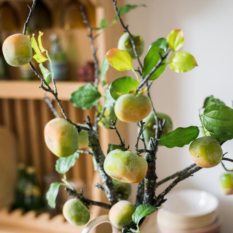 A tall artificial green persimmon fruit stem with four realistic fruits, showcasing vibrant green and yellow colors, perfect for home decor.