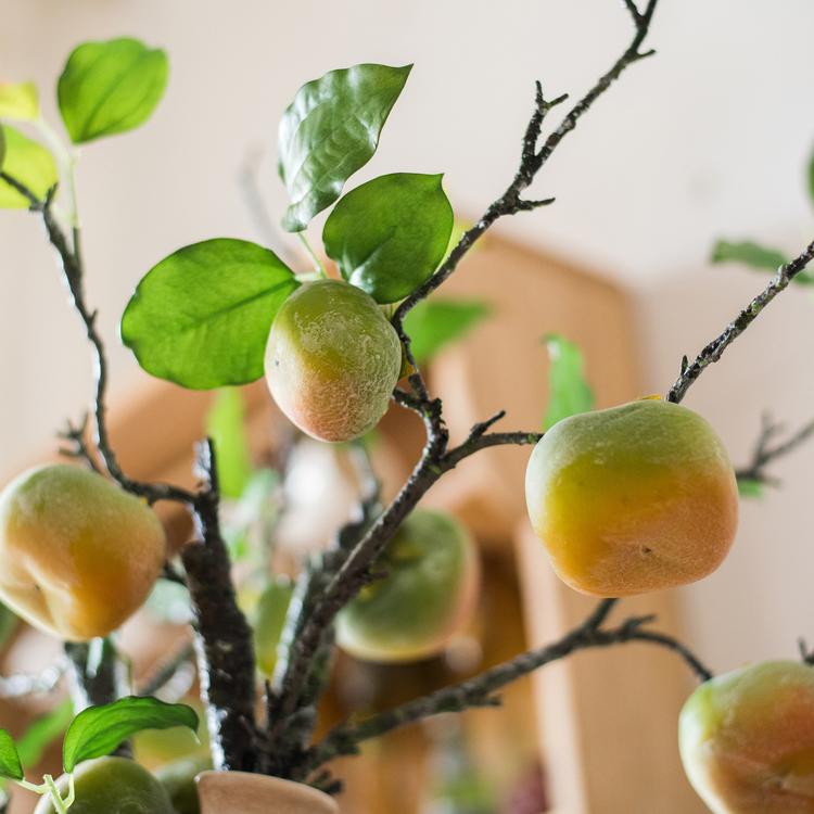 A tall artificial green persimmon fruit stem with four realistic fruits, showcasing vibrant green and yellow colors, perfect for home decor.