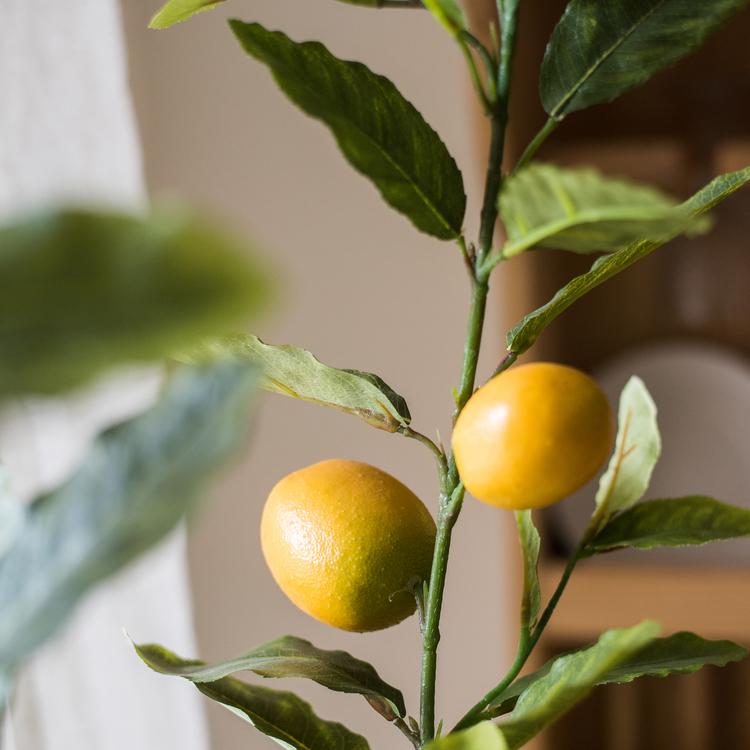 A realistic artificial lemon tree in a black pot, featuring vibrant green leaves and bright yellow lemons, perfect for home decor.