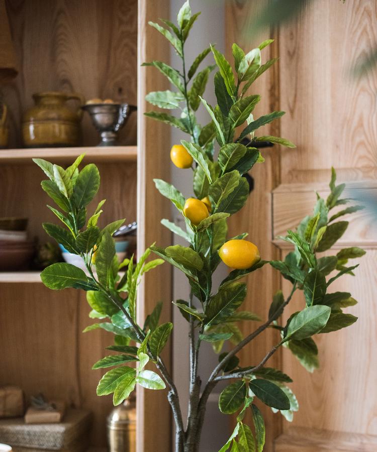 A realistic artificial lemon tree in a black pot, featuring vibrant green leaves and bright yellow lemons, perfect for home decor.