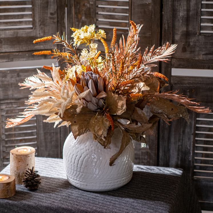 A beautifully arranged Artificial Silk Natural Fall Designer Flower Bouquet featuring protea and fern plants in white, purple, and light brown colors.