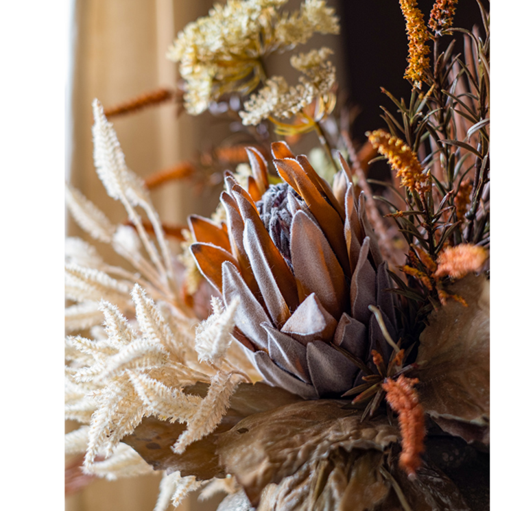 A beautifully arranged Artificial Silk Natural Fall Designer Flower Bouquet featuring protea and fern plants in white, purple, and light brown colors.