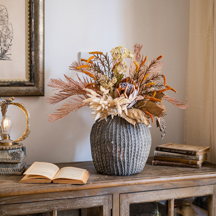 A beautifully arranged Artificial Silk Natural Fall Designer Flower Bouquet featuring protea and fern plants in white, purple, and light brown colors.