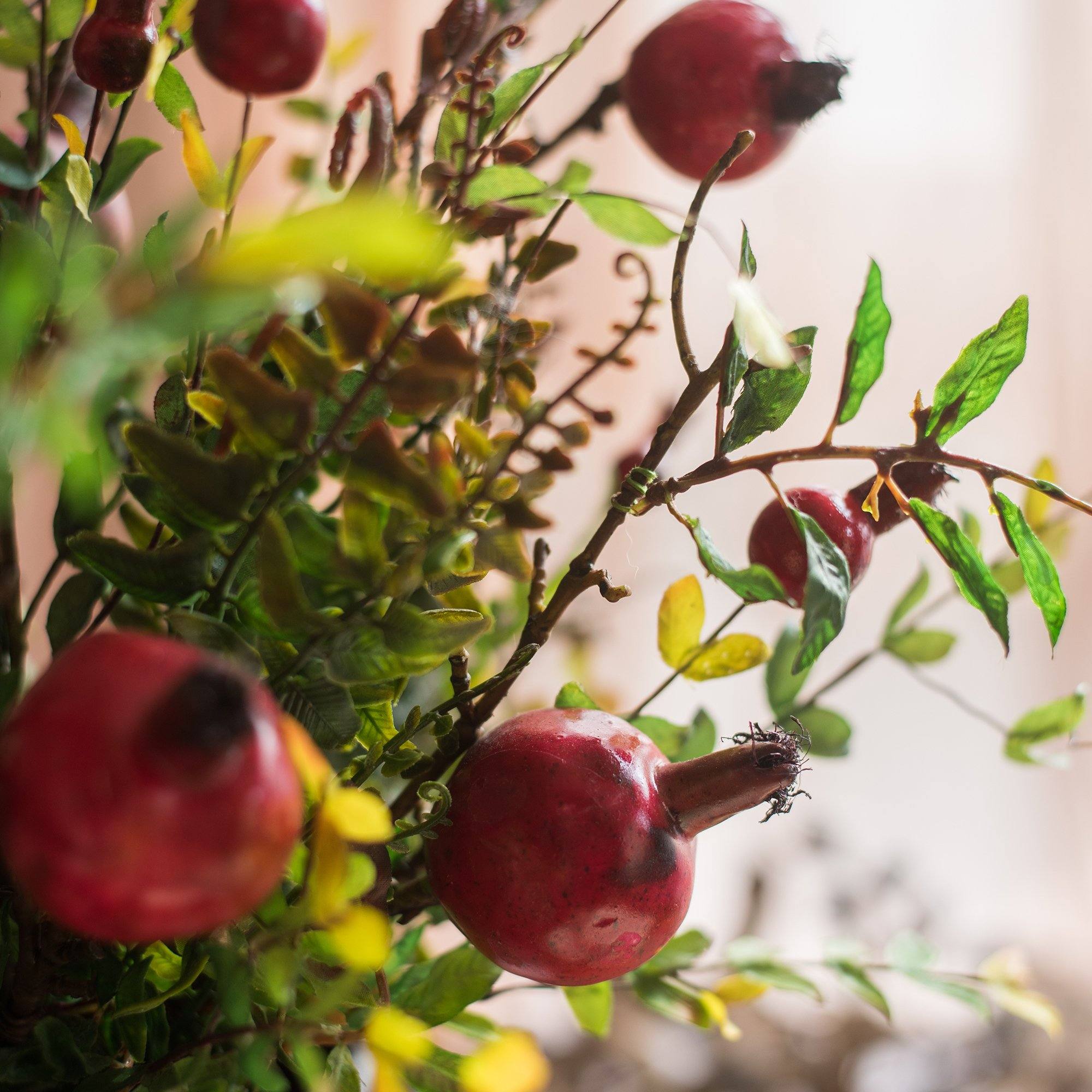 A vibrant 22-inch tall artificial silk bouquet featuring realistic red pomegranate fruits and lush green leaves, perfect for home decor.