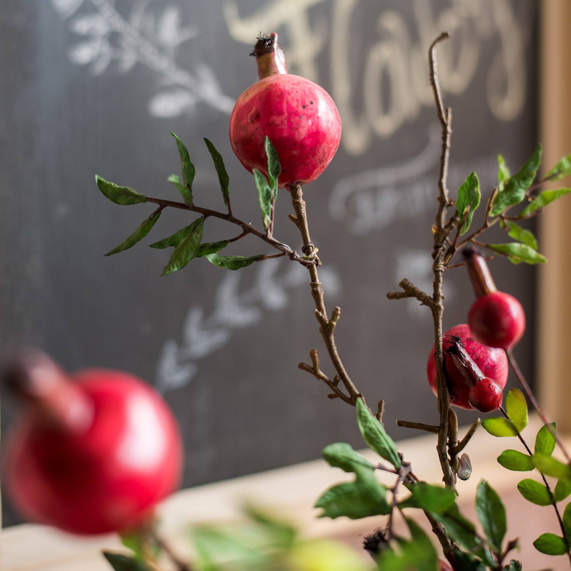 A vibrant 22-inch tall artificial silk bouquet featuring realistic red pomegranate fruits and lush green leaves, perfect for home decor.