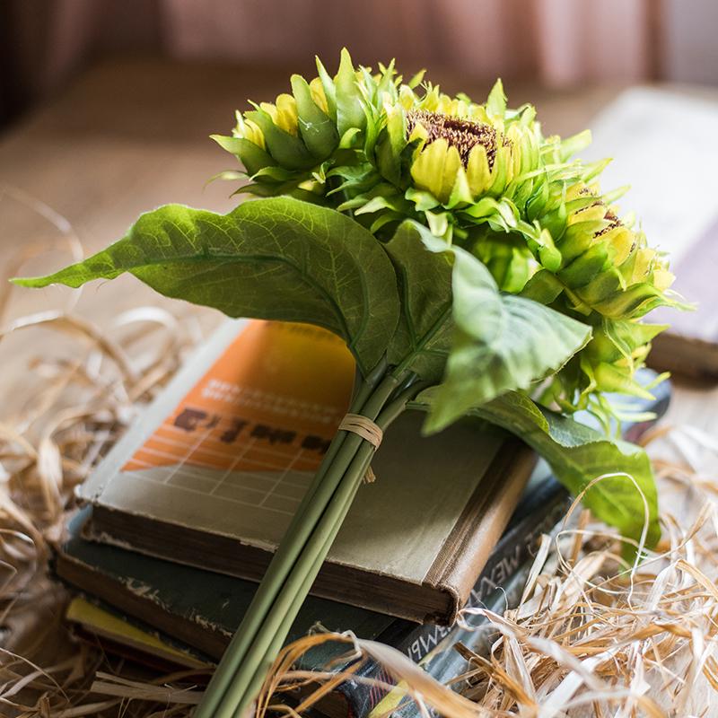 A vibrant artificial silk yellow sunflower bouquet, featuring seven flower stems with rich yellow petals and textured green leaves, standing 13 inches tall.