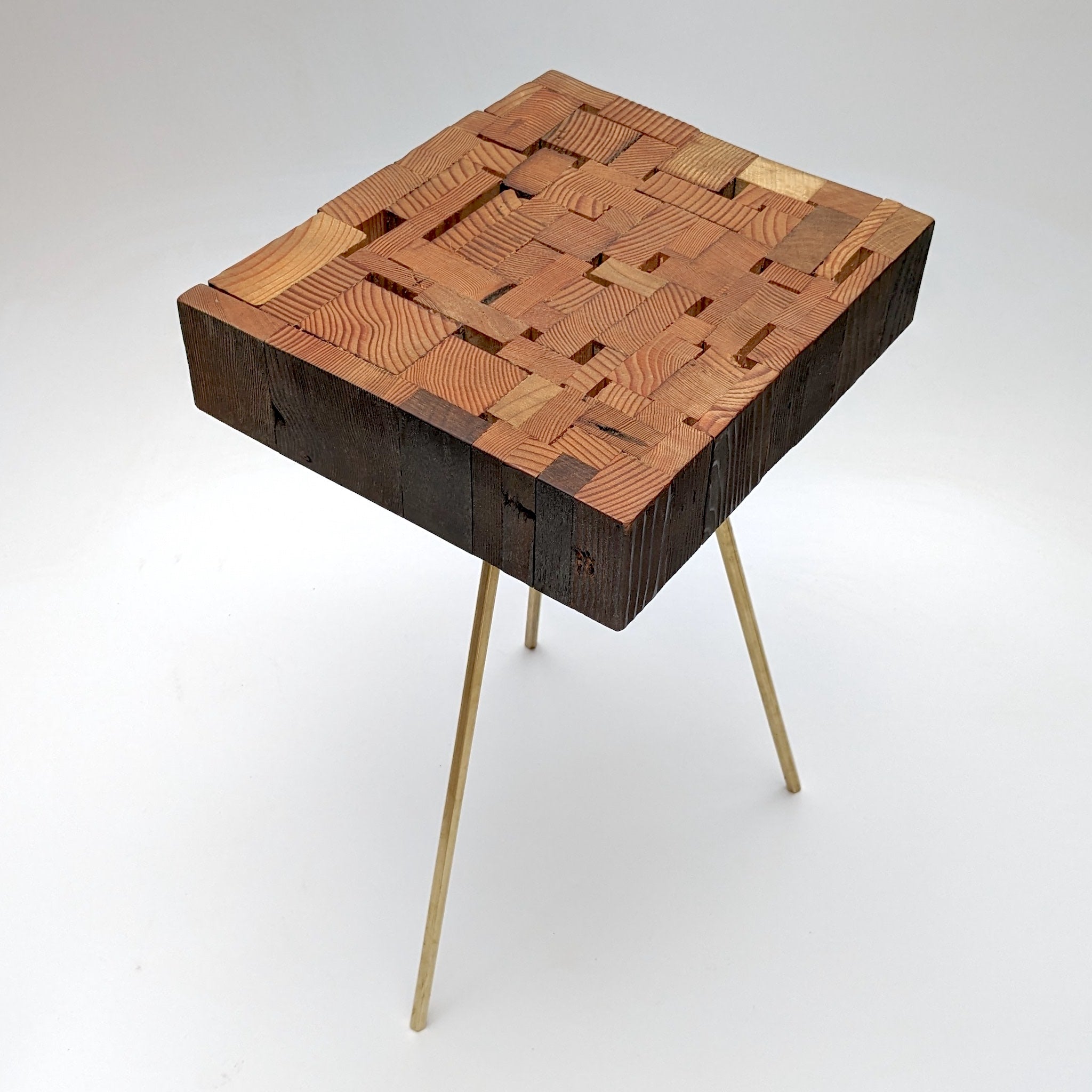 Assemblage side table made from salvaged wood with brass hexagon legs, showcasing unique design and craftsmanship.