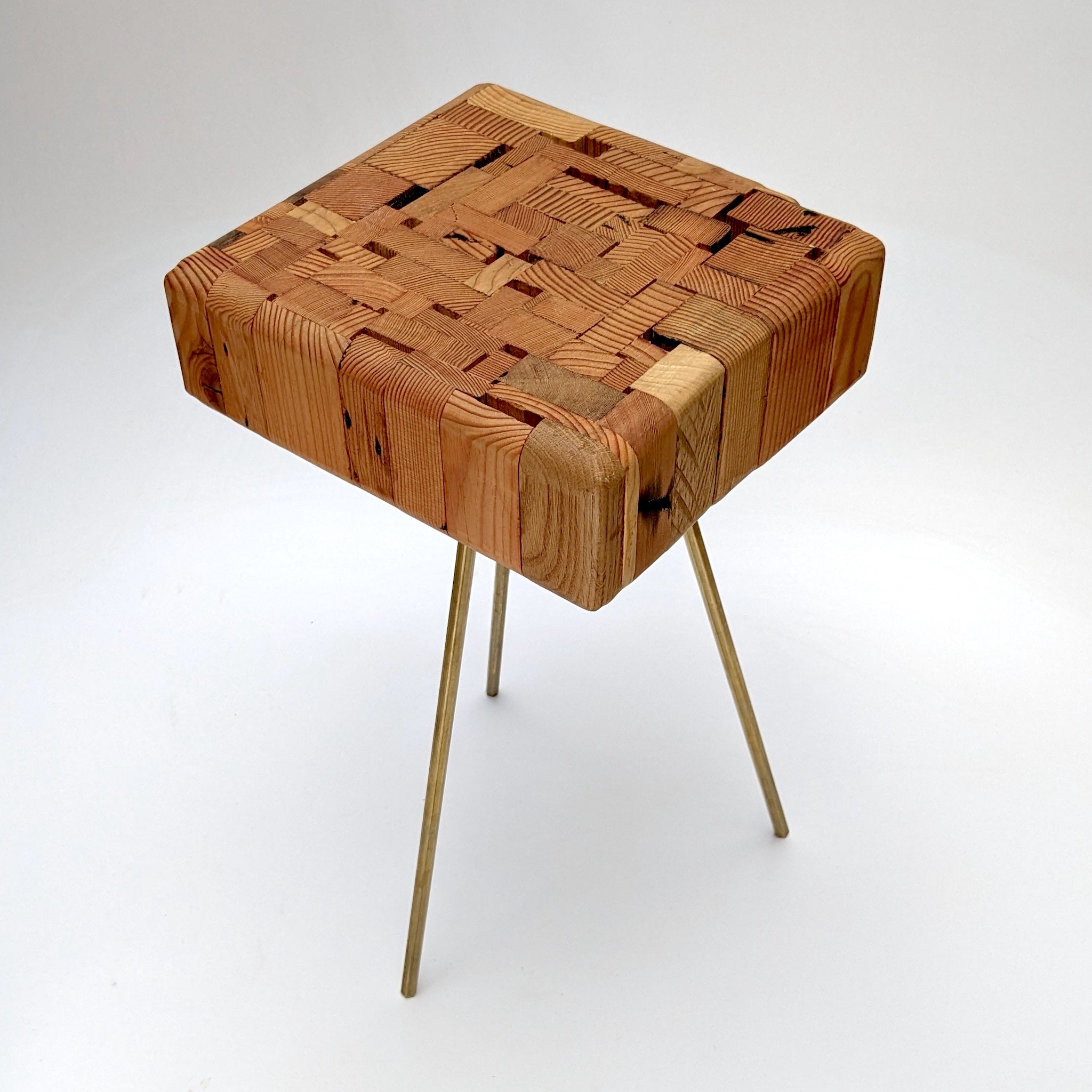 Assemblage side table made from salvaged wood with brass hexagon legs, showcasing unique design and craftsmanship.