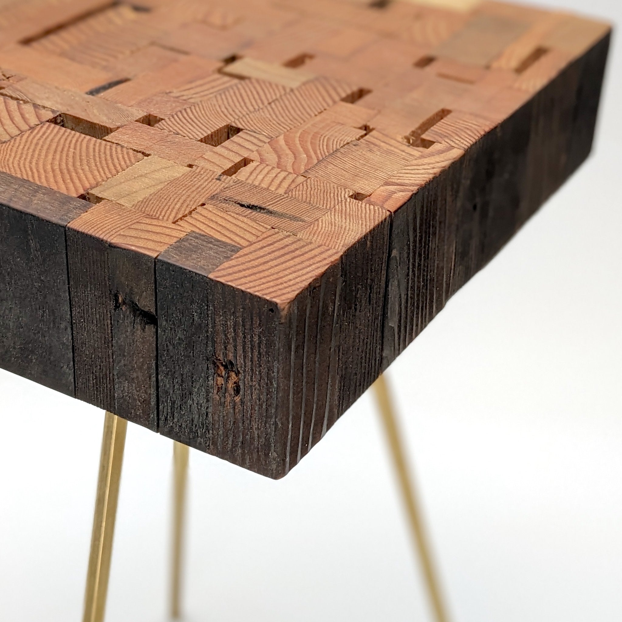 Assemblage side table made from salvaged wood with brass hexagon legs, showcasing unique design and craftsmanship.