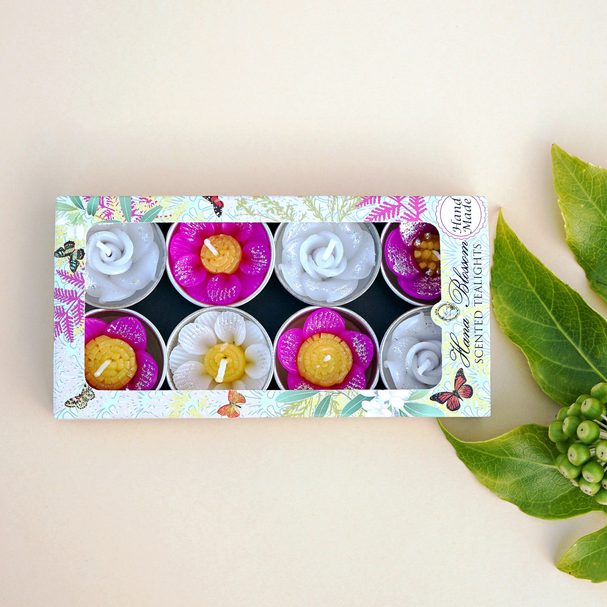 A collection of assorted glitter flower scented tealights in white, pink, and yellow, beautifully arranged in a botanic garden printed box.