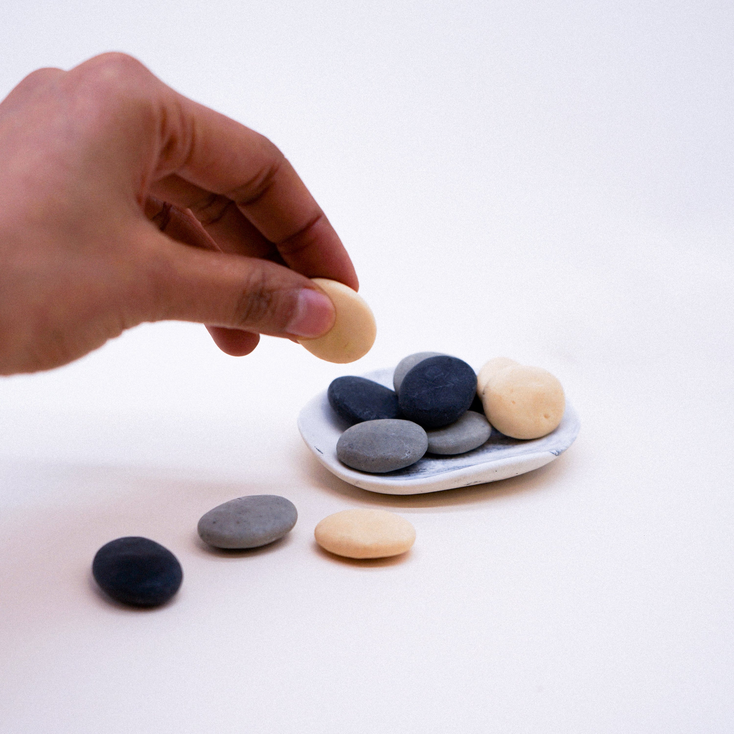 A set of assorted handmade soaps shaped like small pebbles, showcasing their natural design and vibrant colors.