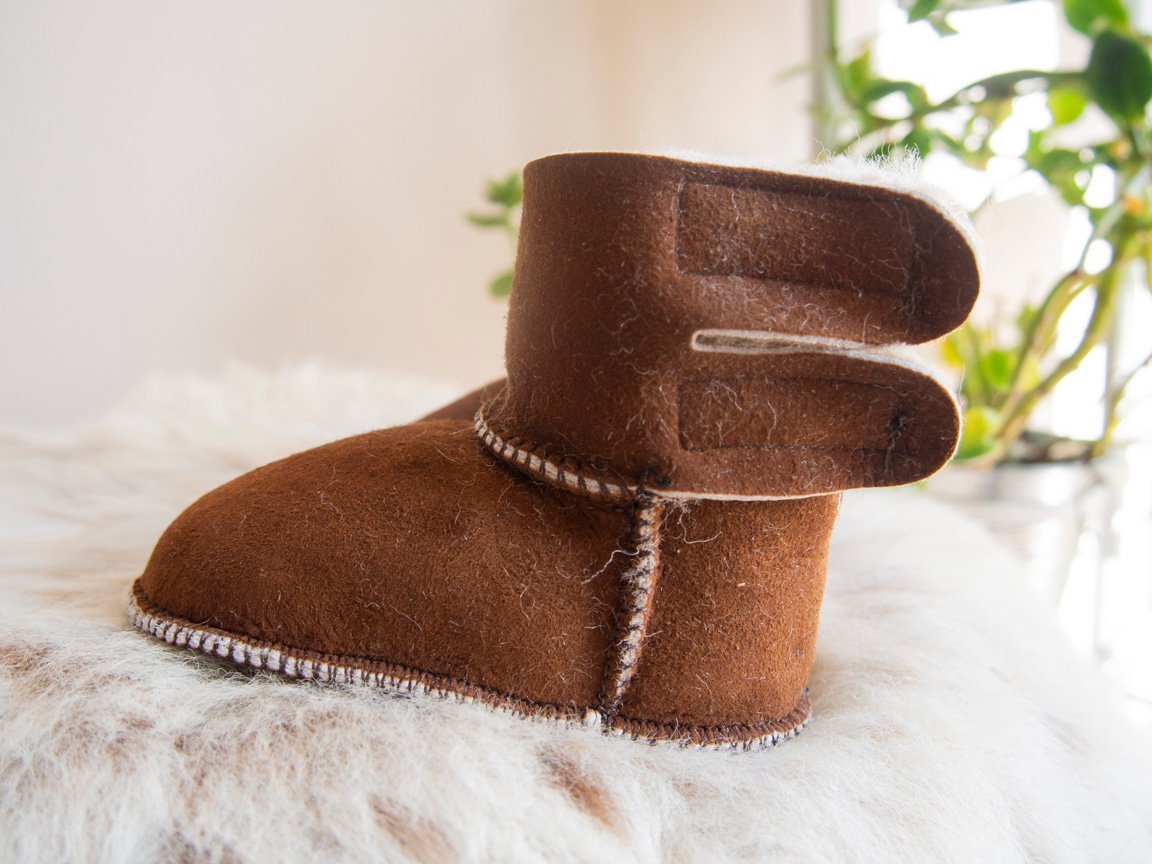 A pair of handmade baby brown sheepskin boots with soft fur lining, designed for comfort and warmth.