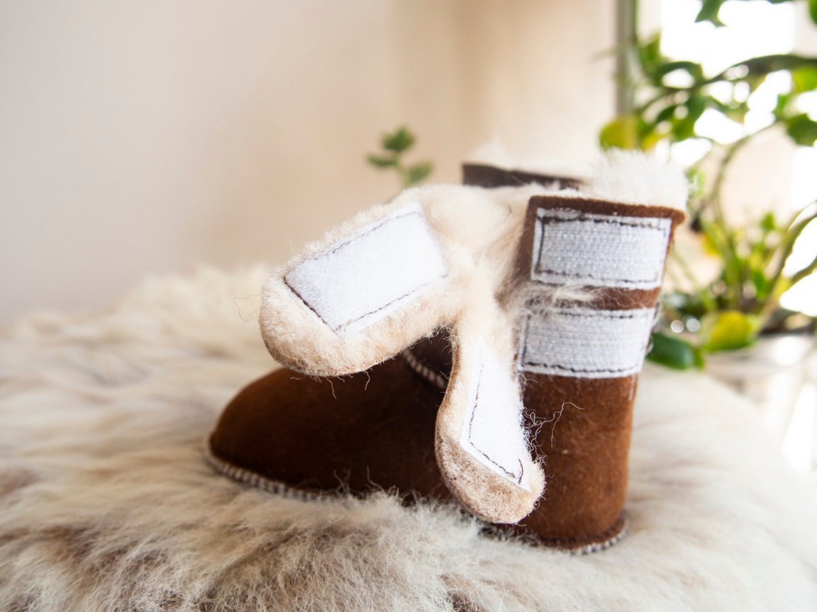 A pair of handmade baby brown sheepskin boots with soft fur lining, designed for comfort and warmth.