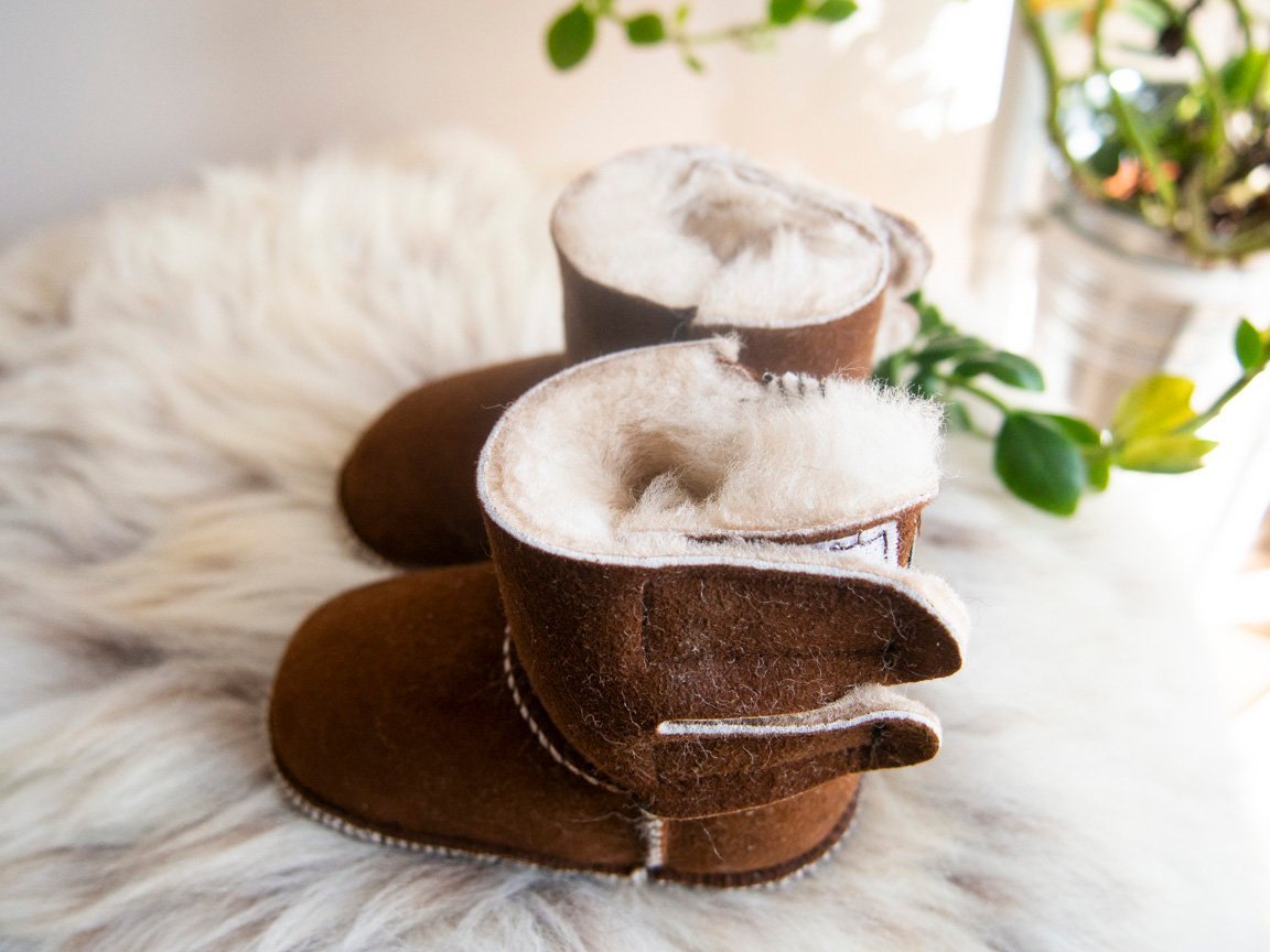 A pair of handmade baby brown sheepskin boots with soft fur lining, designed for comfort and warmth.