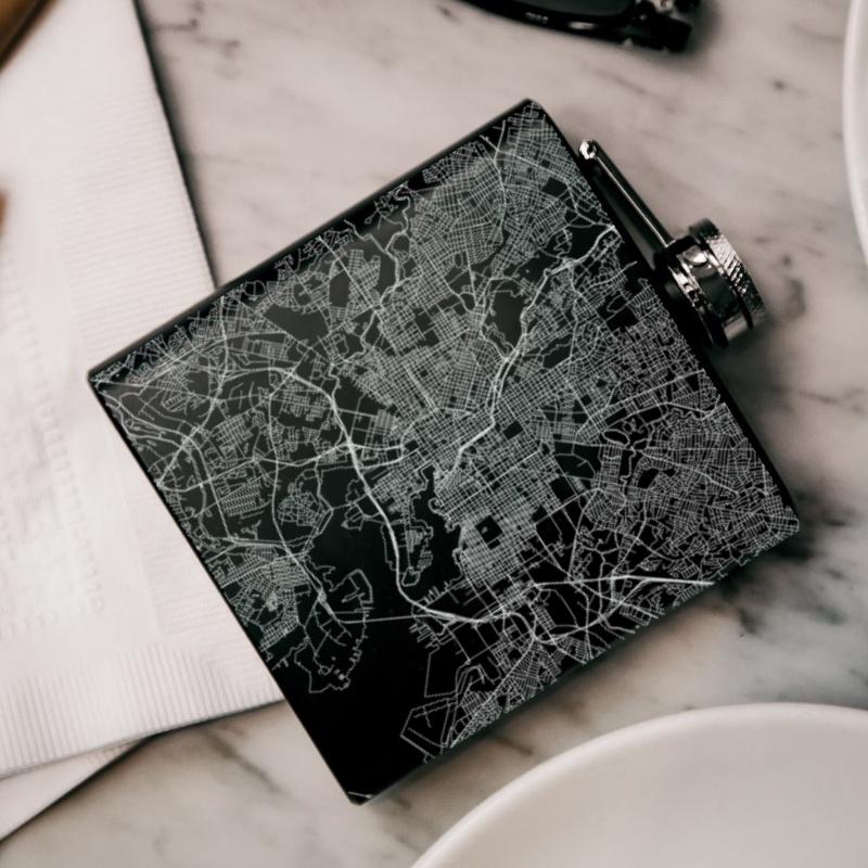 Custom engraved matte black hip flask featuring a Baltimore map and coordinates, complete with a canvas bag and funnel.