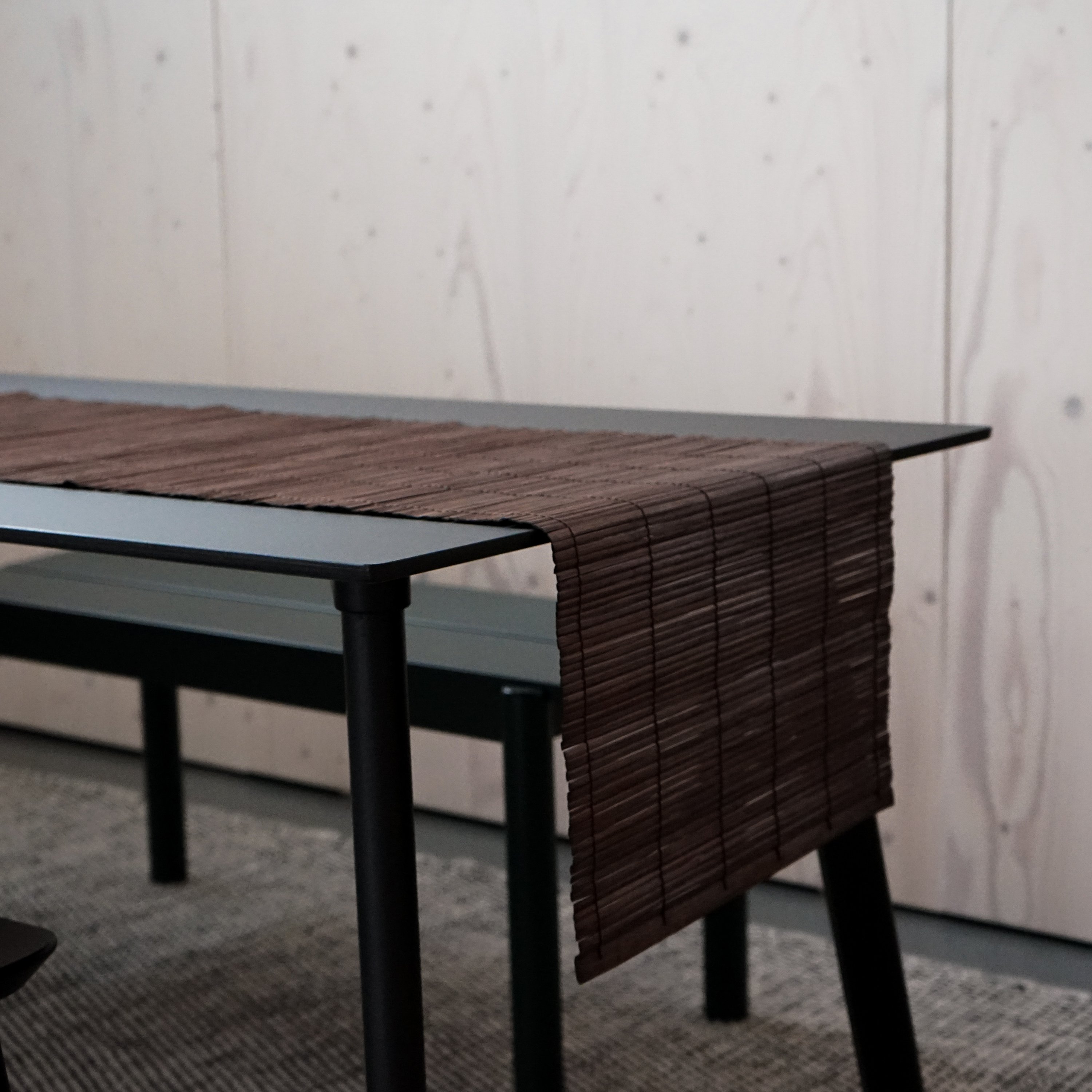 A beautifully handcrafted bamboo table runner in rich brown color, elegantly draped over a dining table, showcasing its natural texture and design.