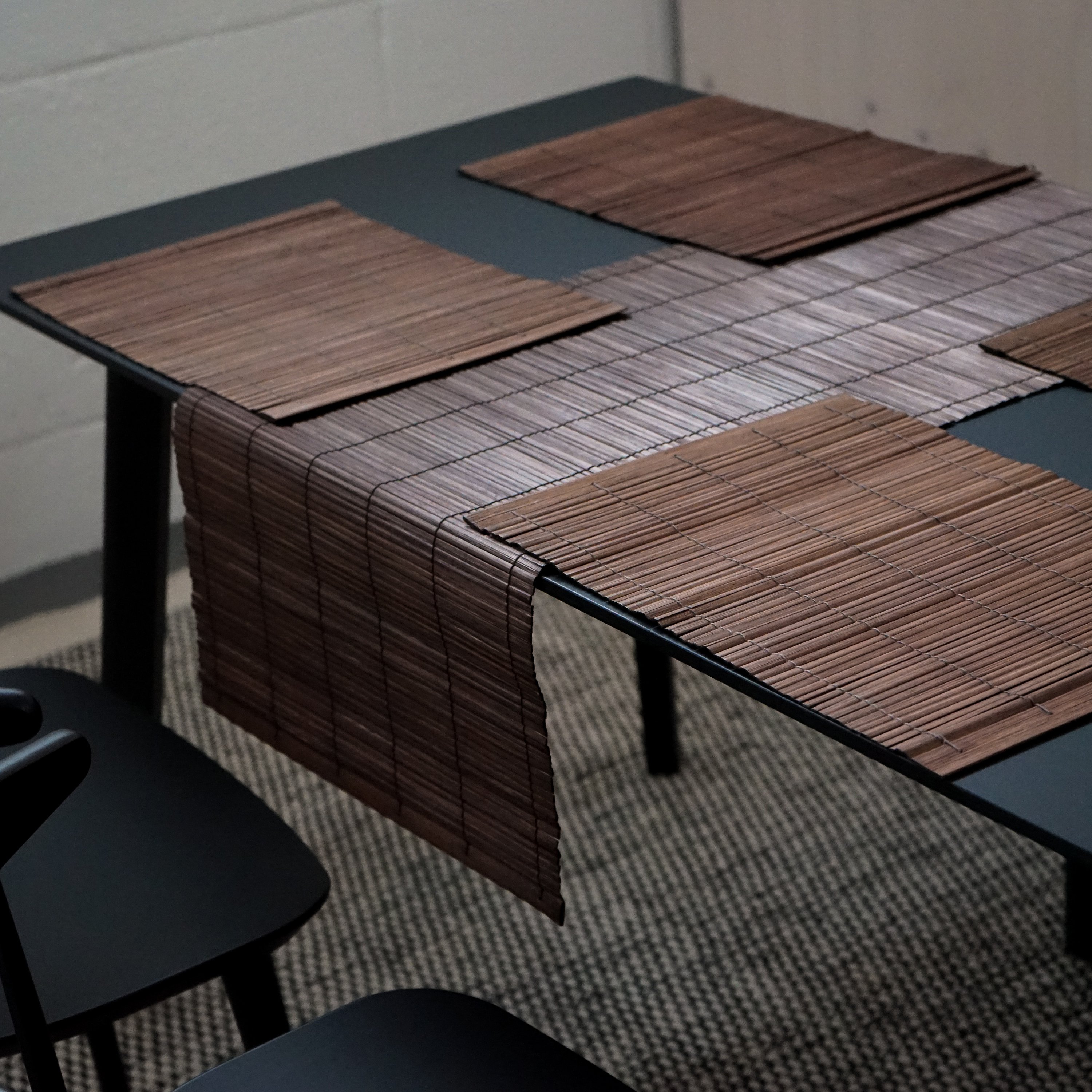 A beautifully handcrafted bamboo table runner in rich brown color, elegantly draped over a dining table, showcasing its natural texture and design.