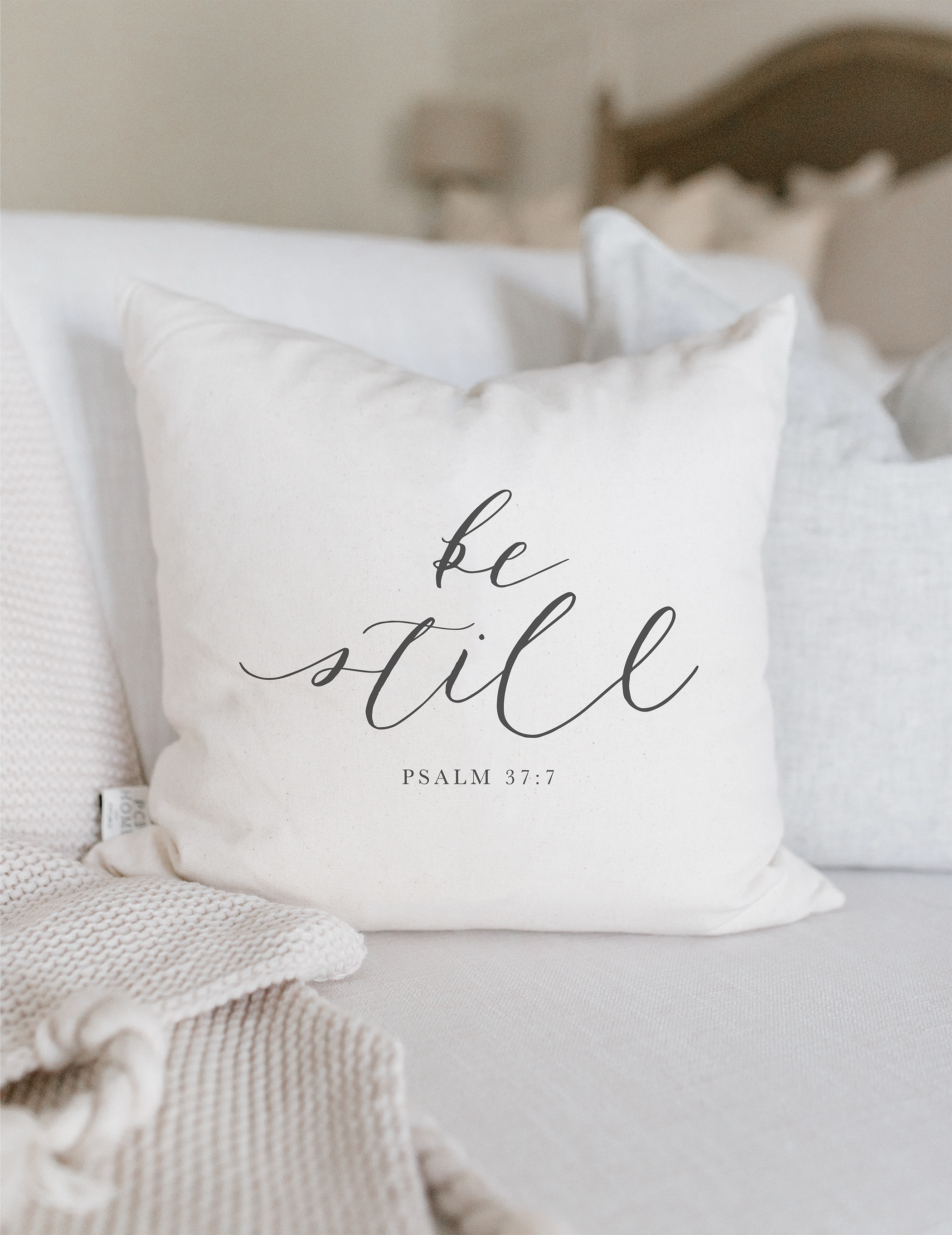 Be Still Verse Pillow featuring unique calligraphy designs on soft cotton fabric, available in white and natural colors.