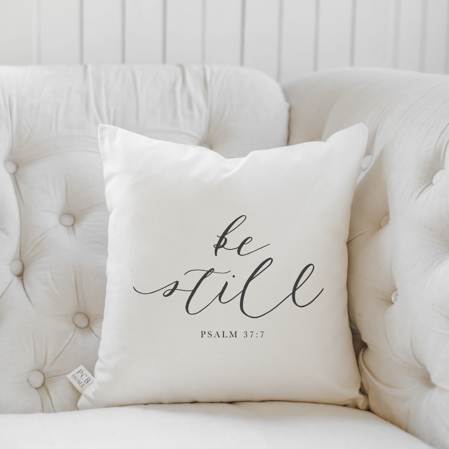 Be Still Verse Pillow featuring unique calligraphy designs on soft cotton fabric, available in white and natural colors.