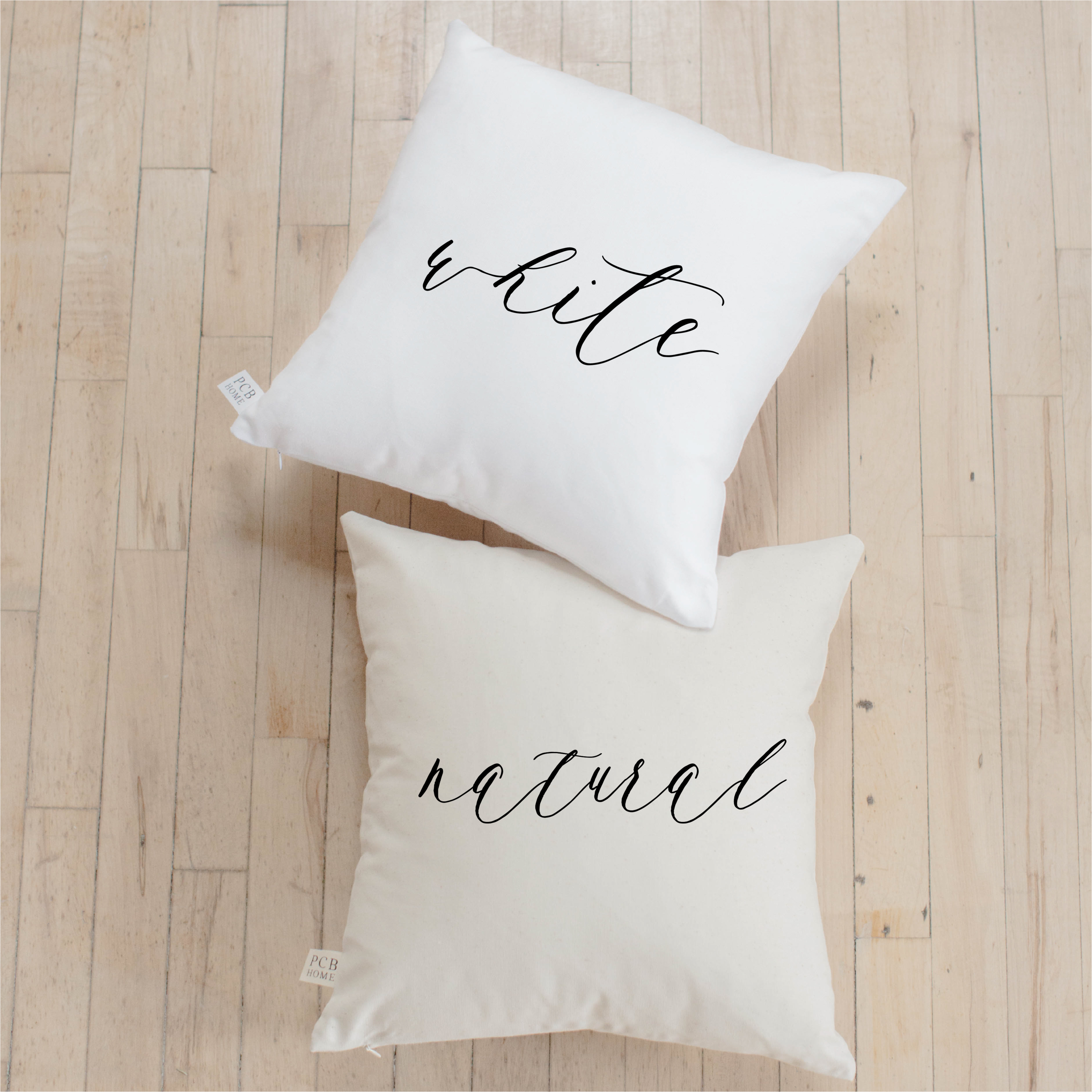 Be Still Verse Pillow featuring unique calligraphy designs on soft cotton fabric, available in white and natural colors.