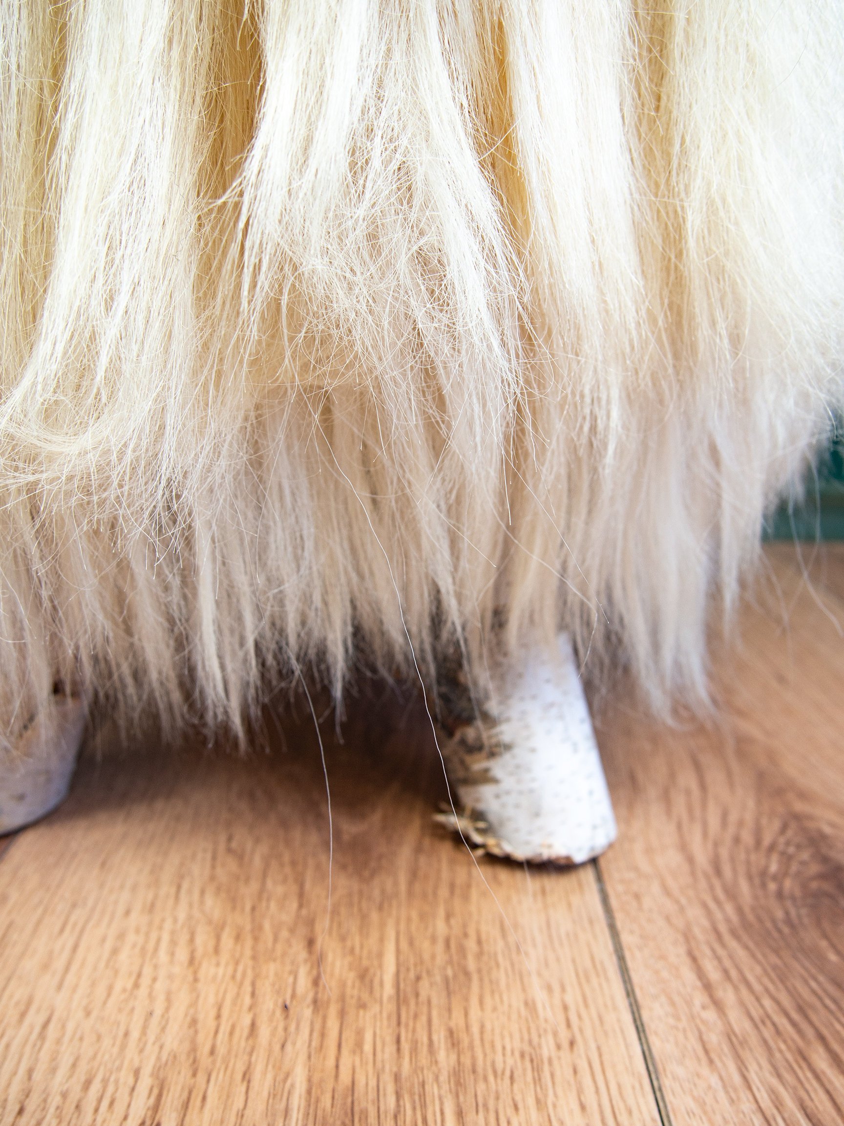 Birch wood and cream sheepskin ottoman showcasing its fluffy texture and elegant design, perfect for home decor.