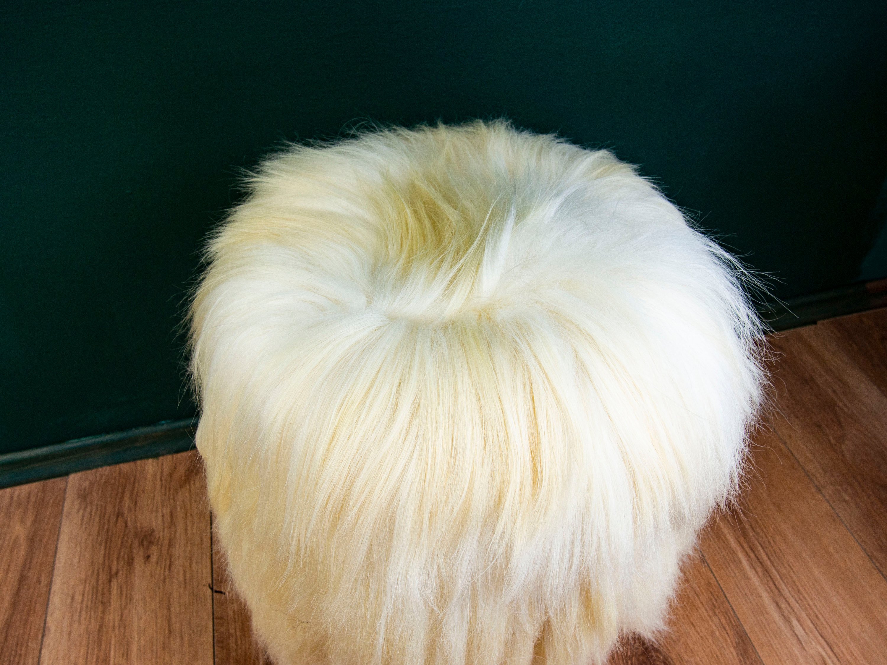 Birch wood and cream sheepskin ottoman showcasing its fluffy texture and elegant design, perfect for home decor.