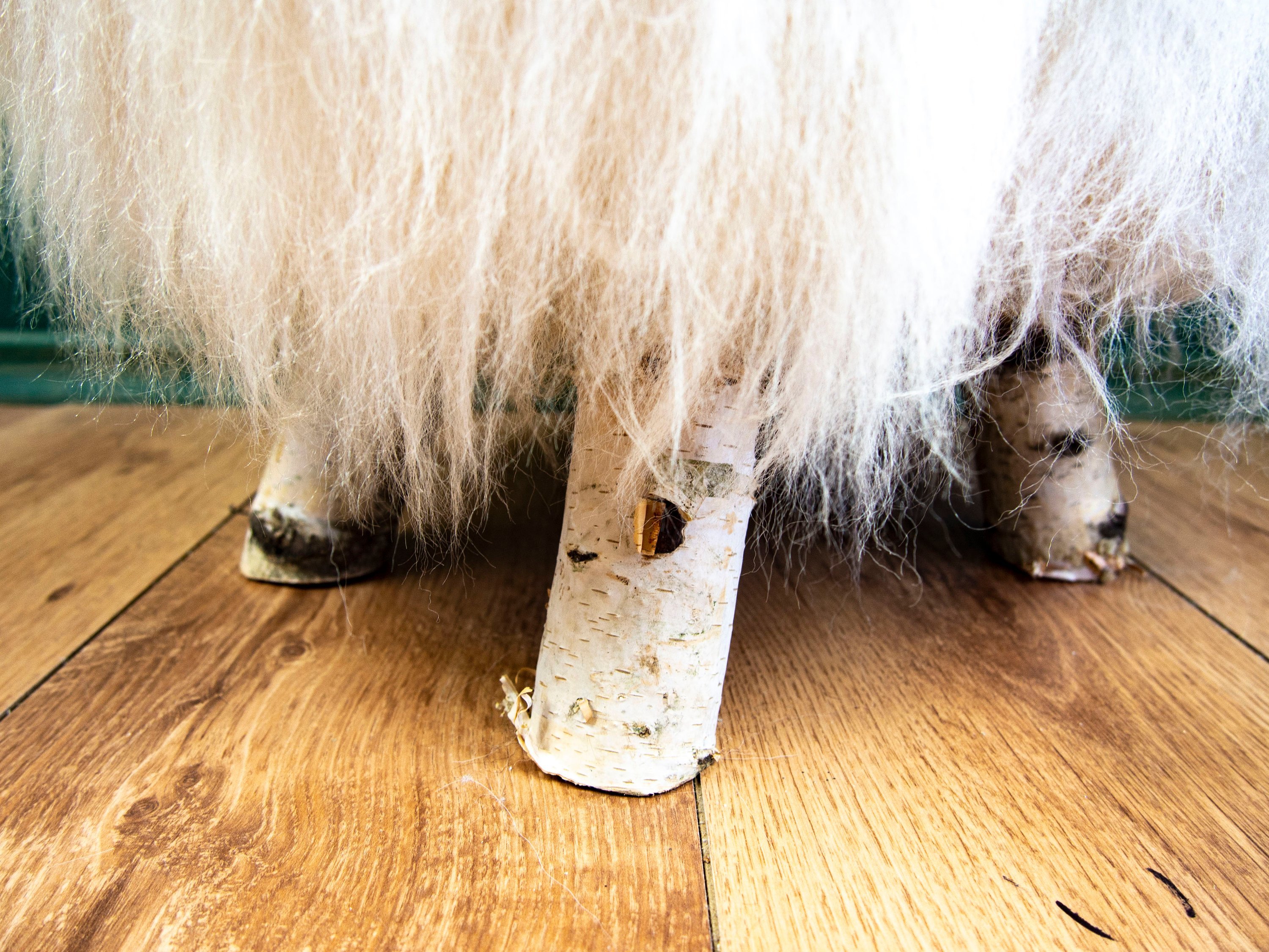 Birch Wood and Ivory Sheepskin Ottoman showcasing its fluffy texture and natural wood base, perfect for home decor.