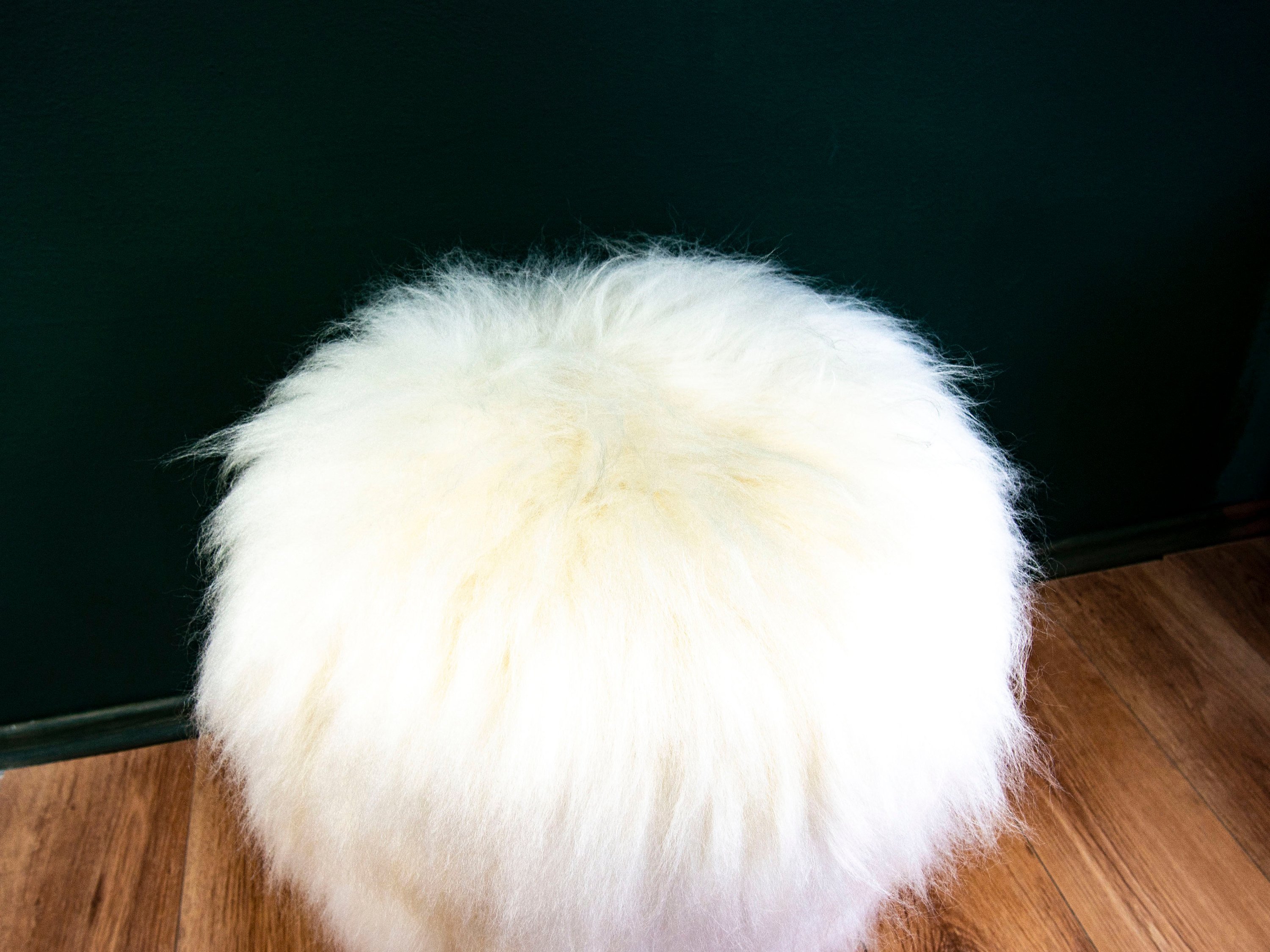 Birch Wood and Ivory Sheepskin Ottoman showcasing its fluffy texture and natural wood base, perfect for home decor.