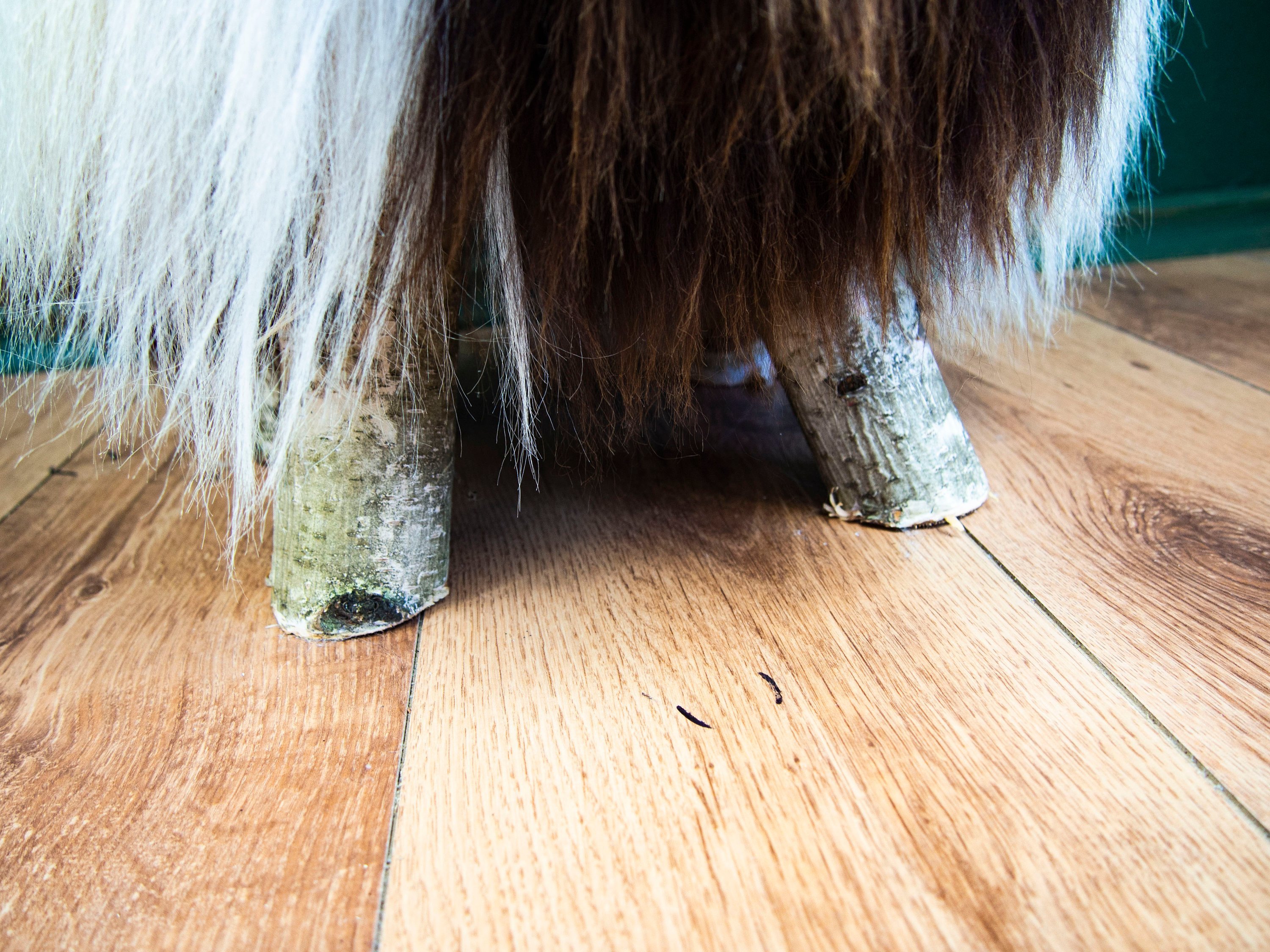 Birch wood ottoman upholstered with fluffy Jacob sheepskin, showcasing its elegant design and natural materials.