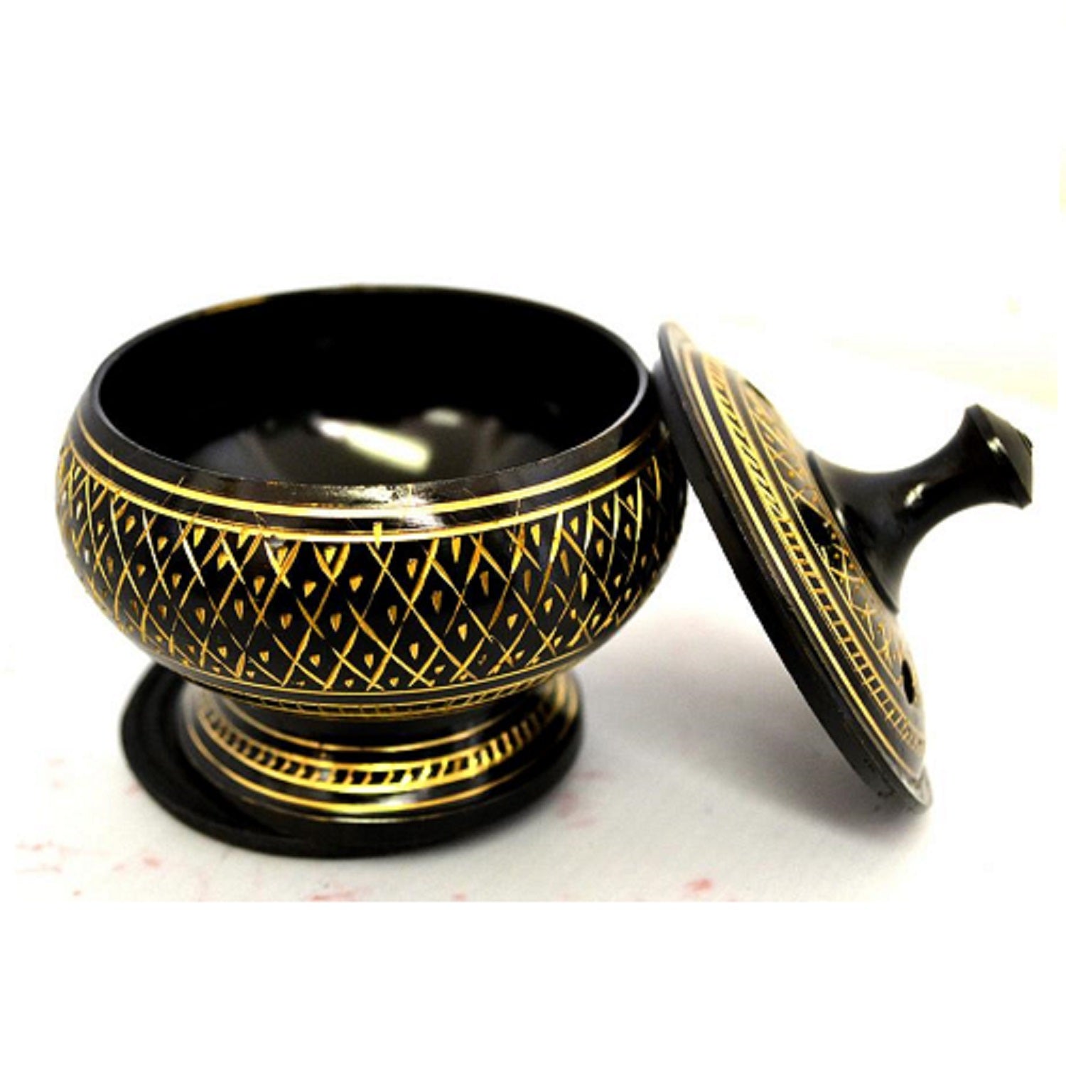 A beautifully designed black and gold brass incense burner with a removable lid and net, accompanied by a wooden coaster.