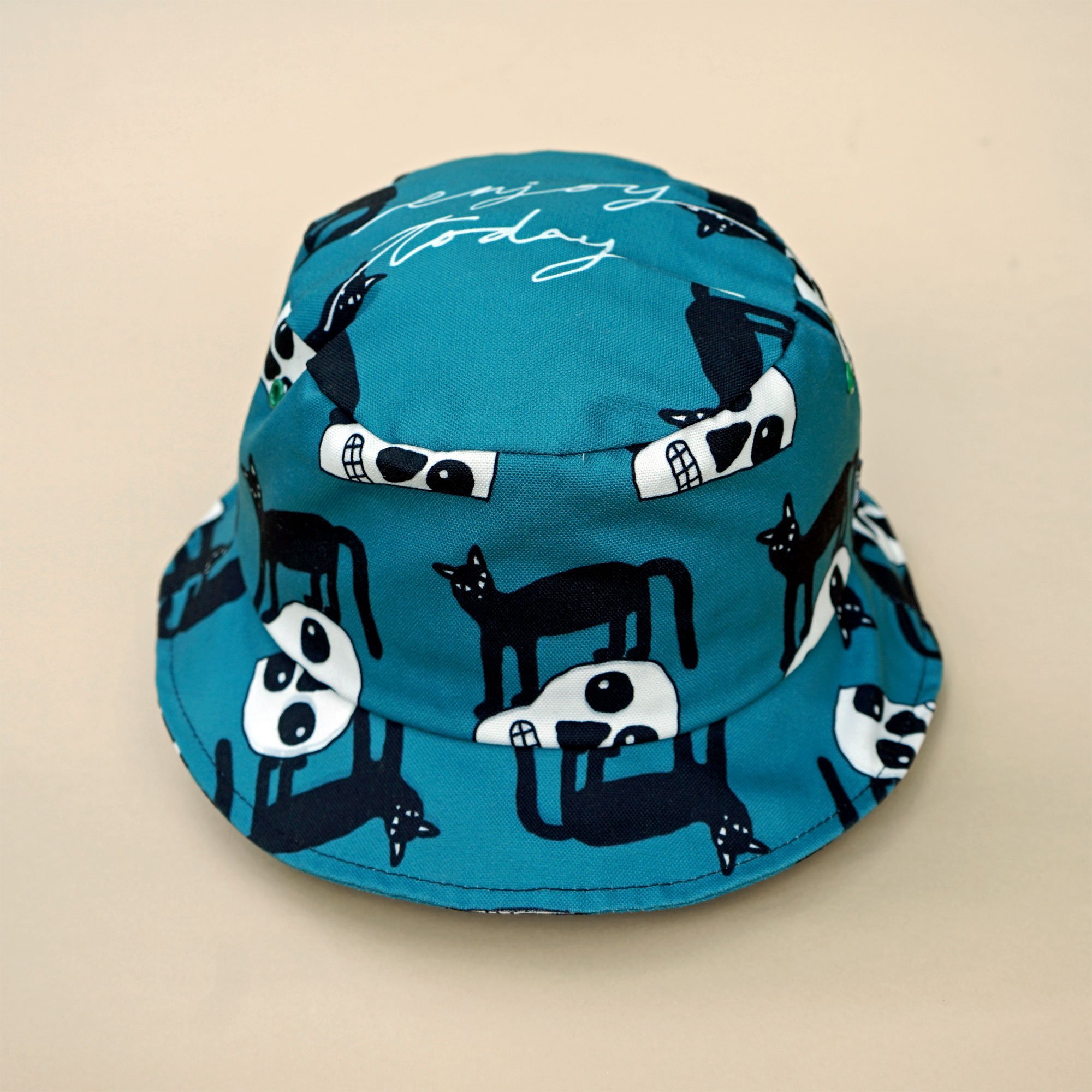 A stylish teal bucket hat featuring a playful black cat design, perfect for casual outings.