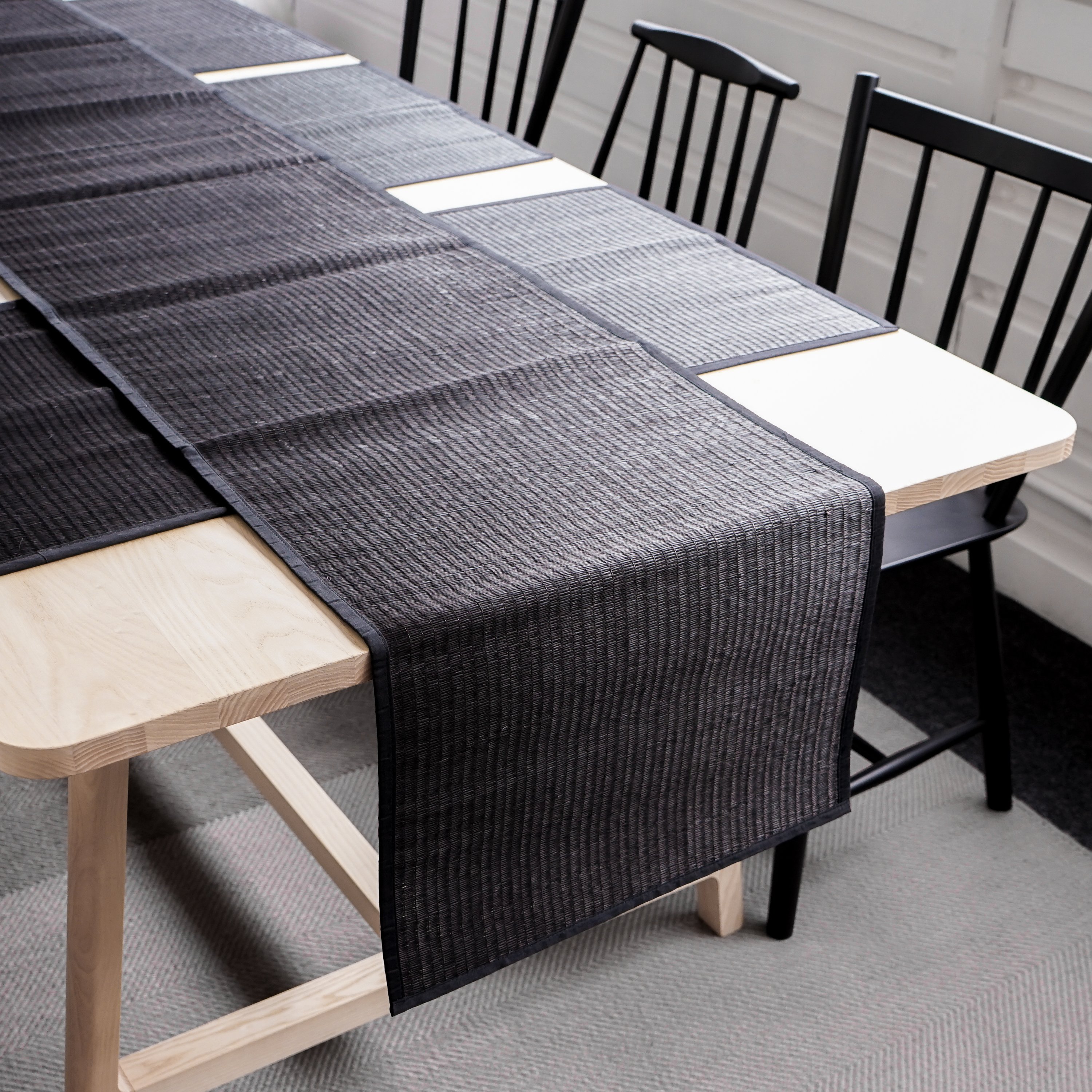 Elegant Black Reed Table Runner on a dining table, showcasing its handmade texture and cotton trim.