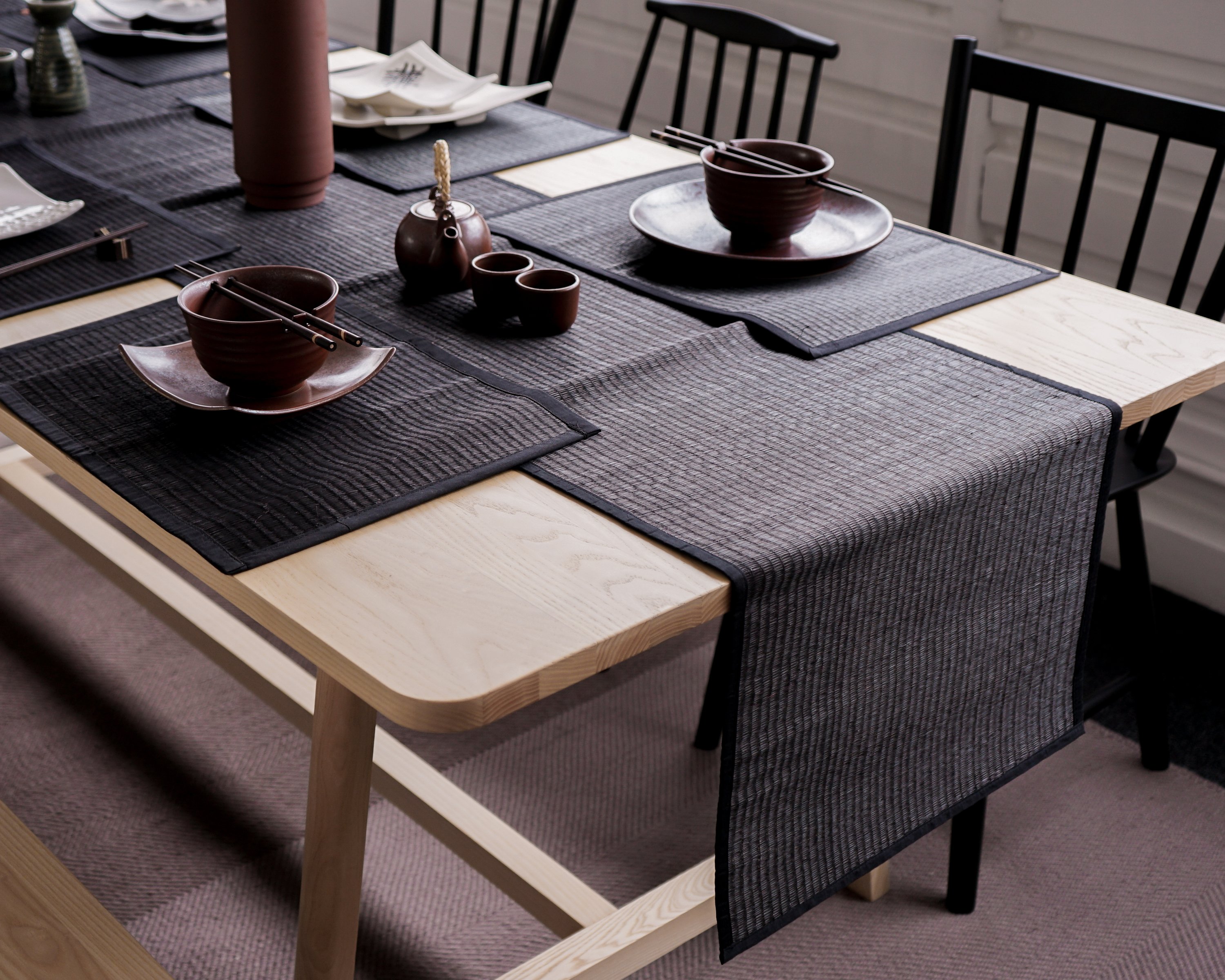 Elegant Black Reed Table Runner on a dining table, showcasing its handmade texture and cotton trim.