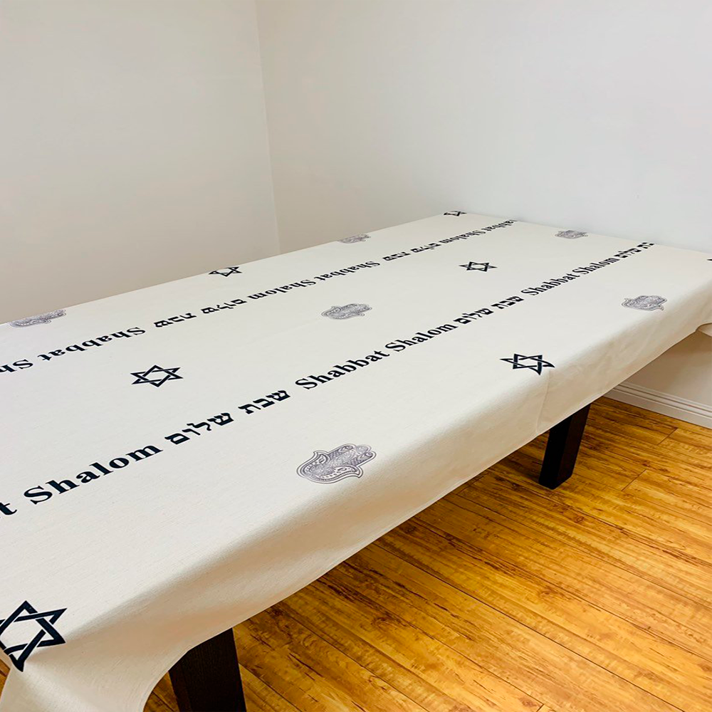 Elegant Black Shabbat Shalom tablecloth featuring Hebrew and English stripes, Magen David and Hamsa details, made from linen-cotton blend.