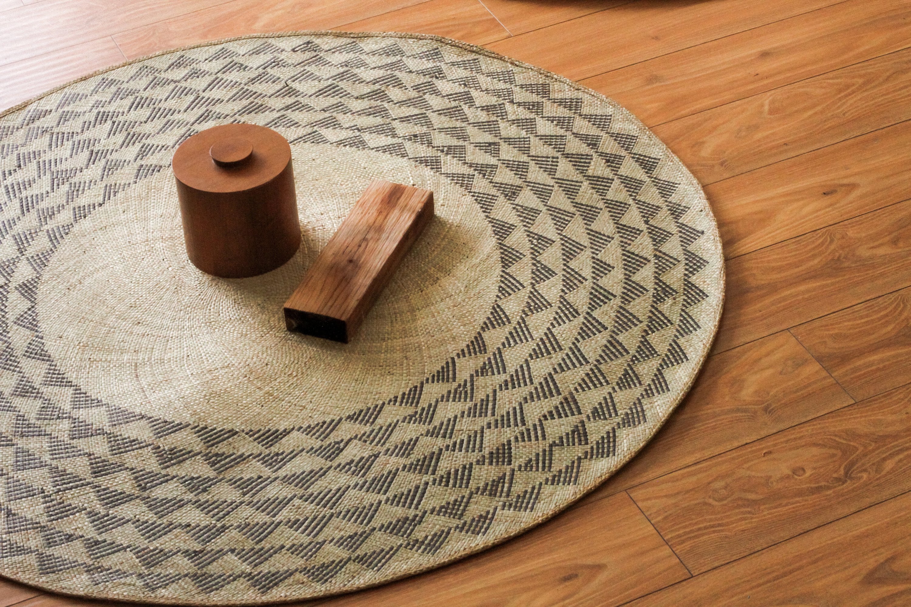 Black Triangle Mat, a 4-foot round rug made from natural fibers with a striking black triangle pattern, perfect for indoor and outdoor use.