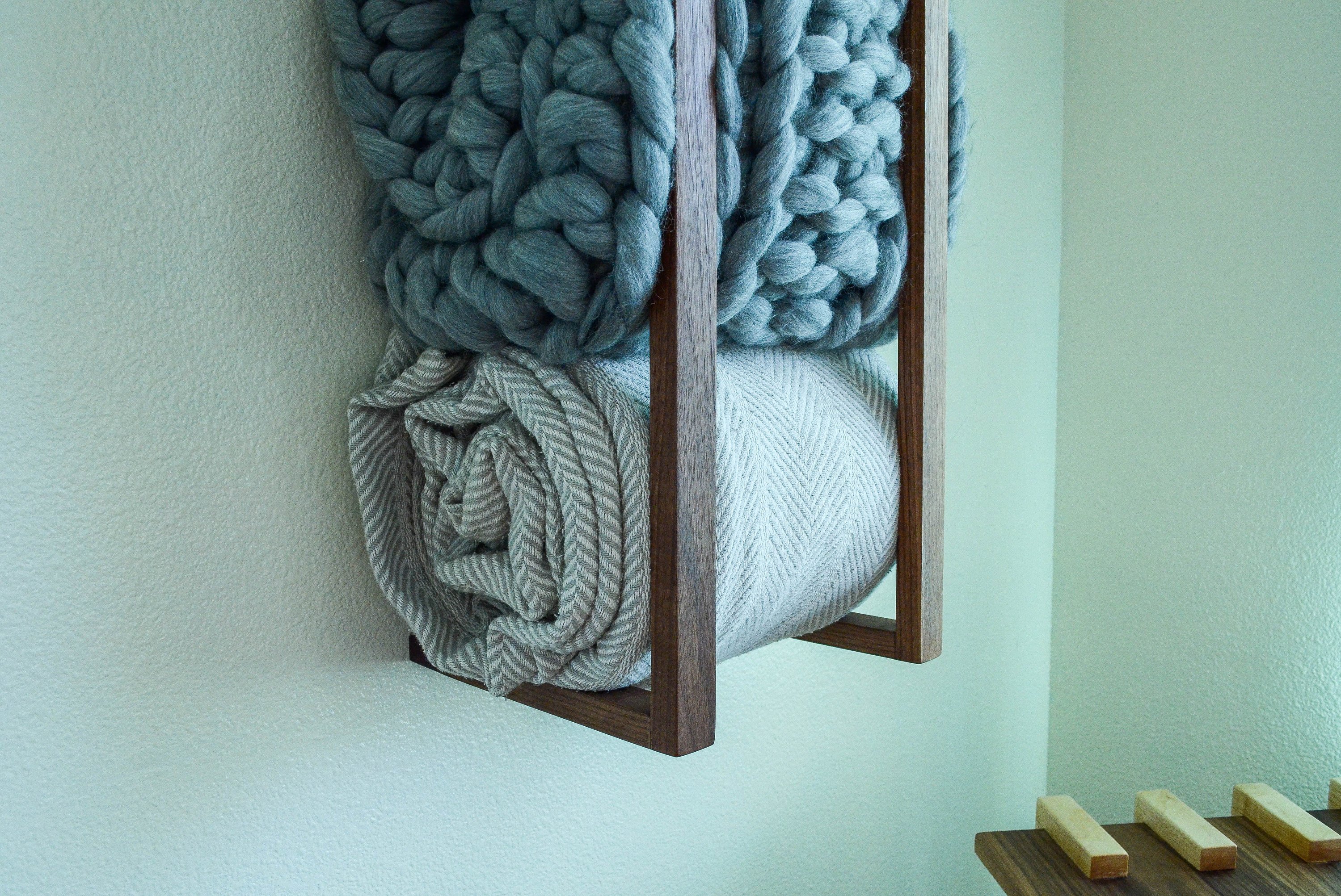 Modern and minimalist blanket wall rack made from American Walnut, showcasing its elegant design and functionality.