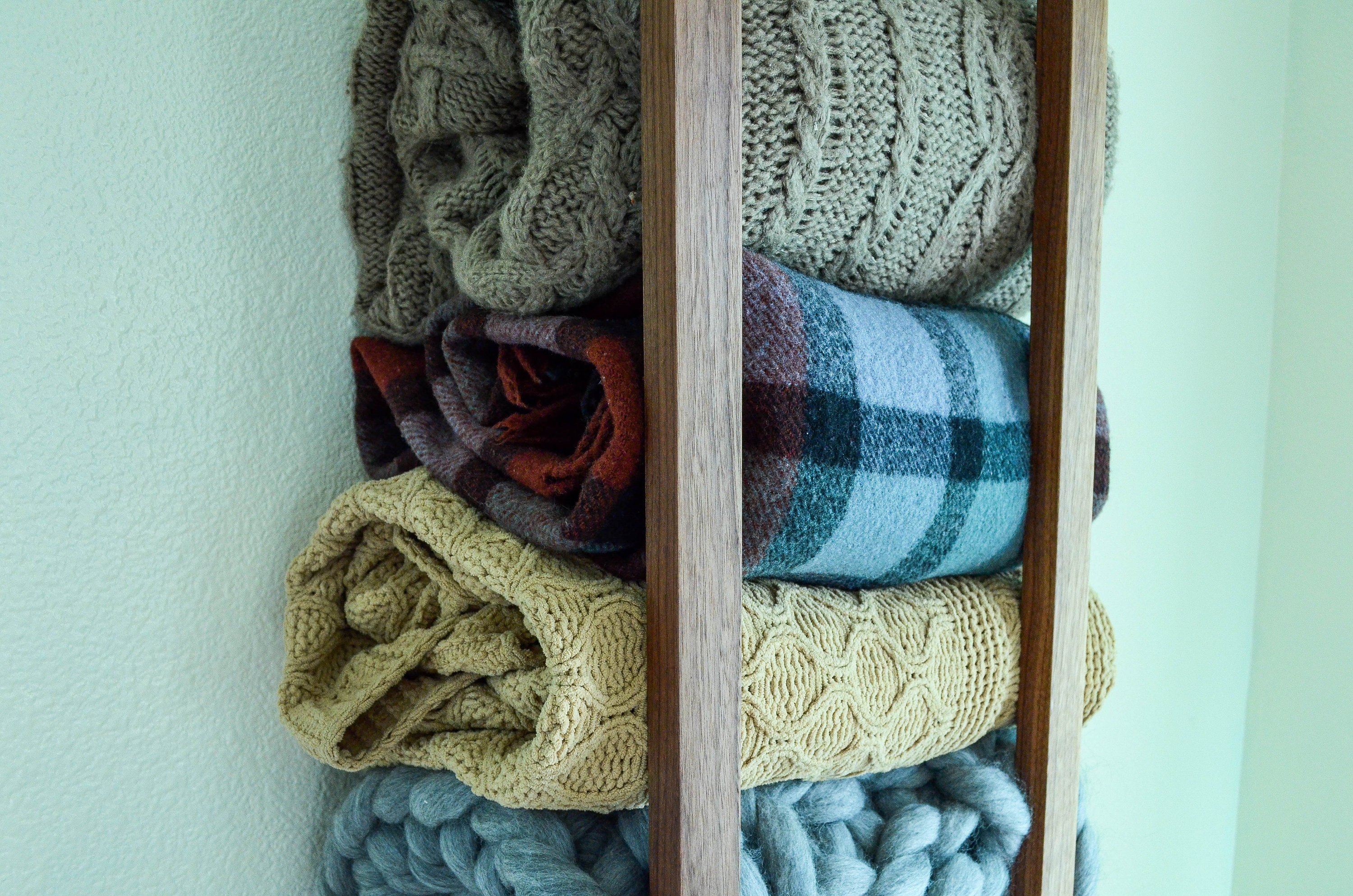 Modern and minimalist blanket wall rack made from American Walnut, showcasing its elegant design and functionality.