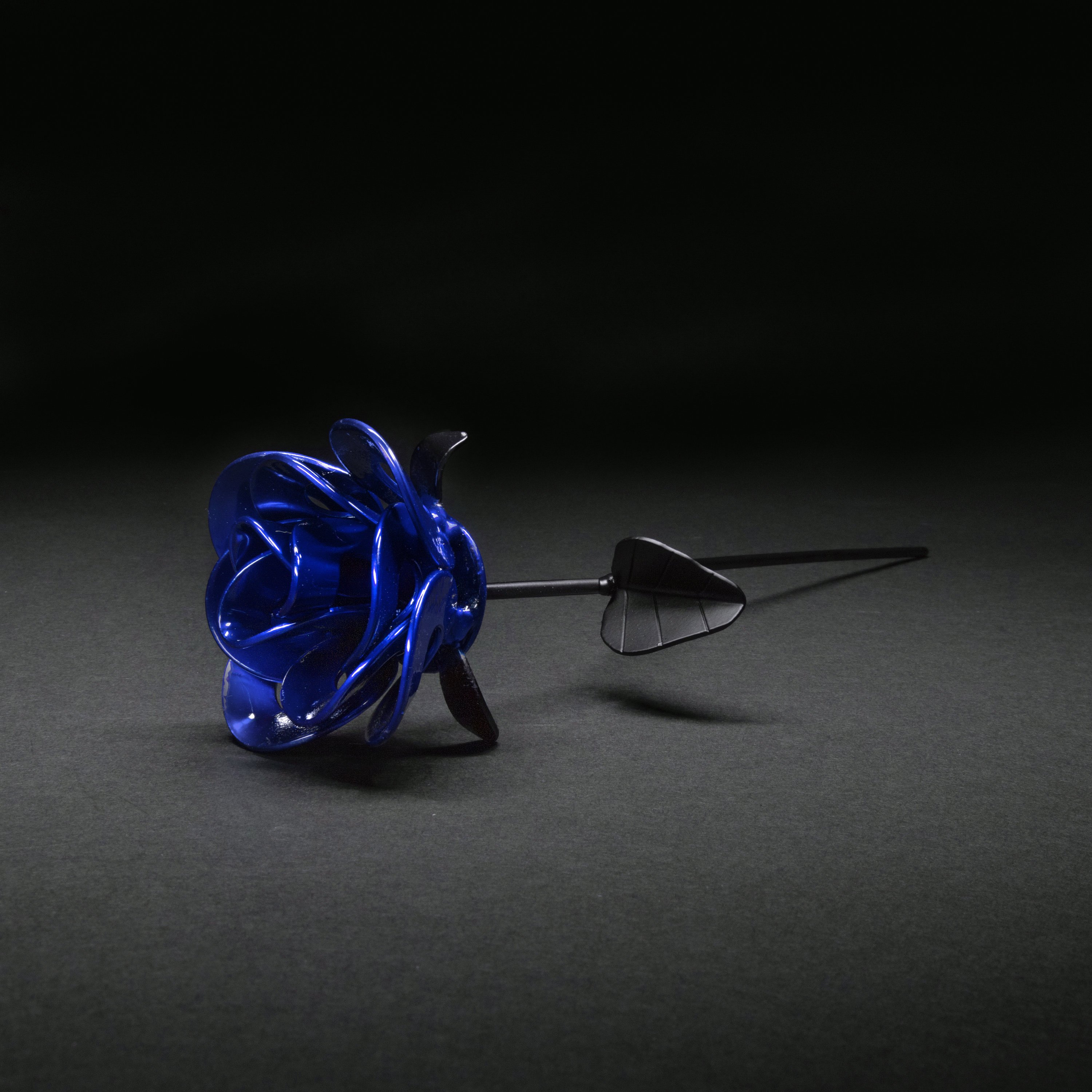 A handcrafted blue and black metal rose made from recycled materials, showcasing intricate welded details and a lustrous finish.