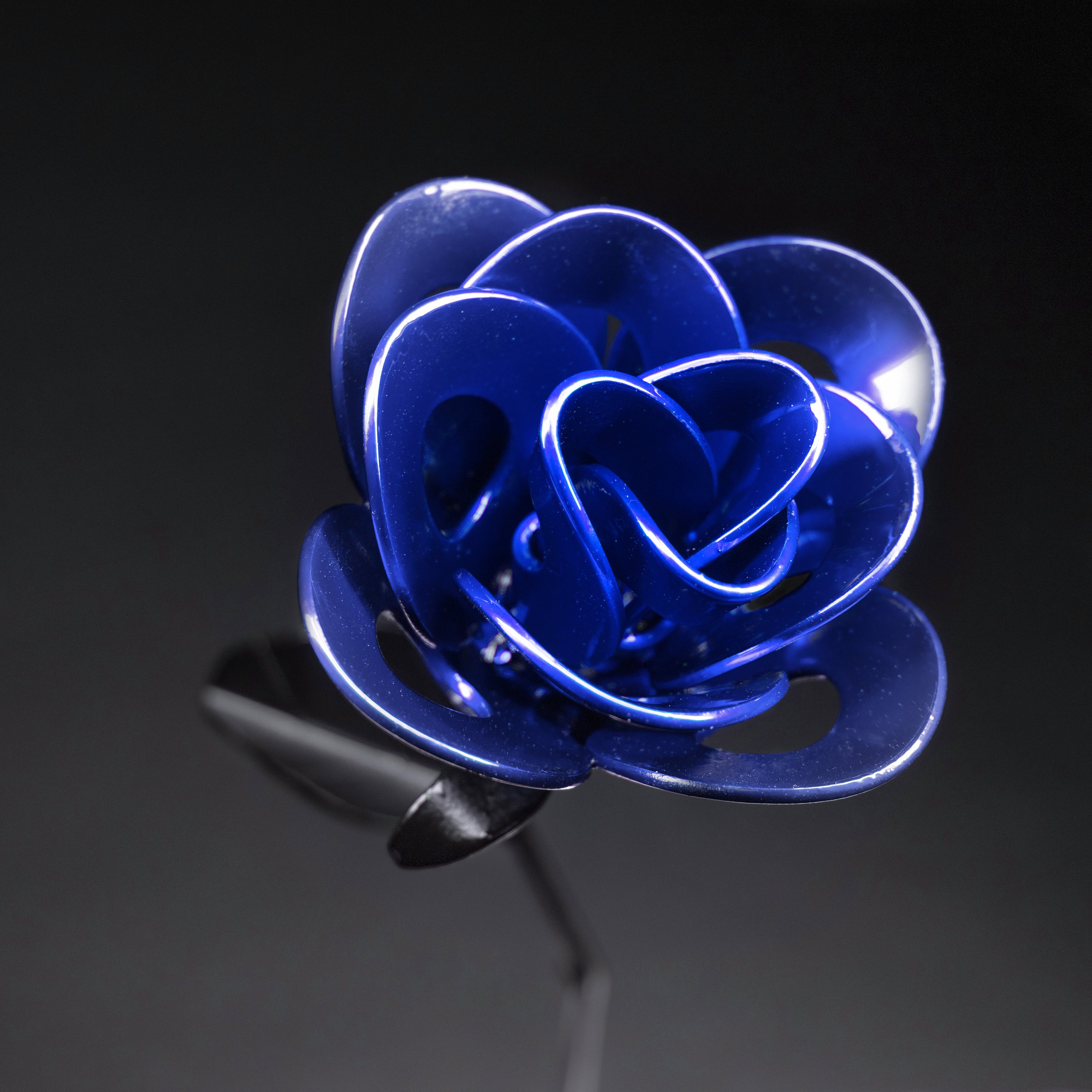 A handcrafted blue and black metal rose made from recycled materials, showcasing intricate welded details and a lustrous finish.