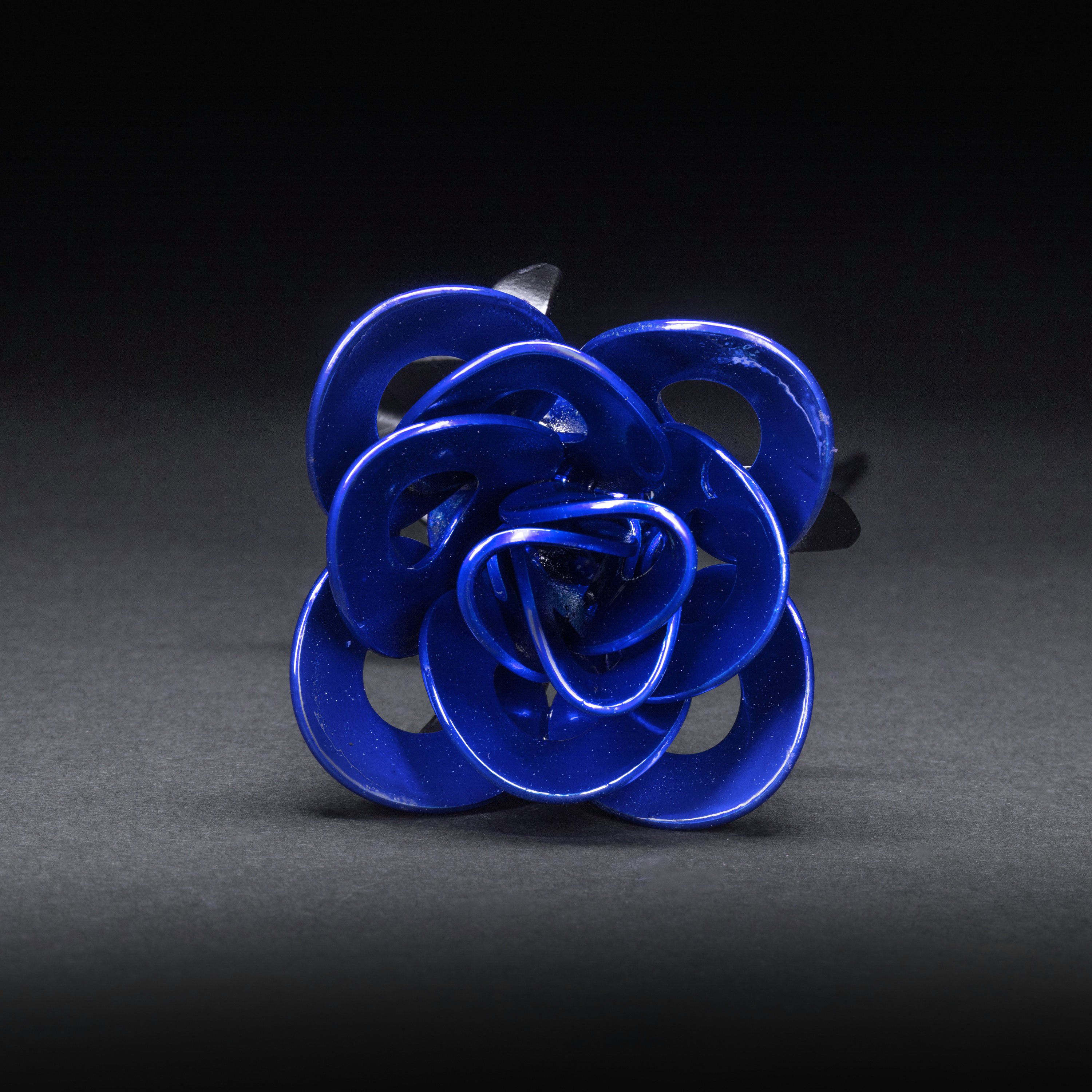 A handcrafted blue and black metal rose made from recycled materials, showcasing intricate welded details and a lustrous finish.